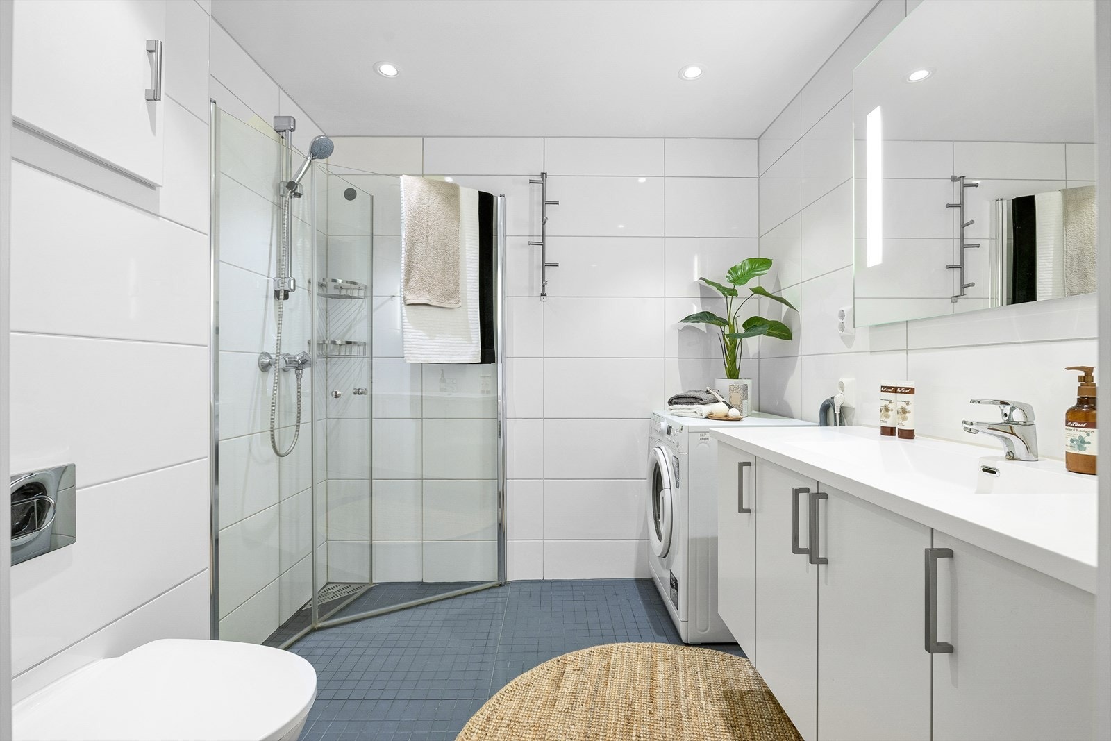 Baderommet er på 4 m² og har innredning levert av HTH. Badet er flislagt fra topp til tå med varme i gulv og har moderne downlights i tak. Baderomsinnredningen har god plass til lagring av både håndduker og andre baderomsartikler. Galleribilde