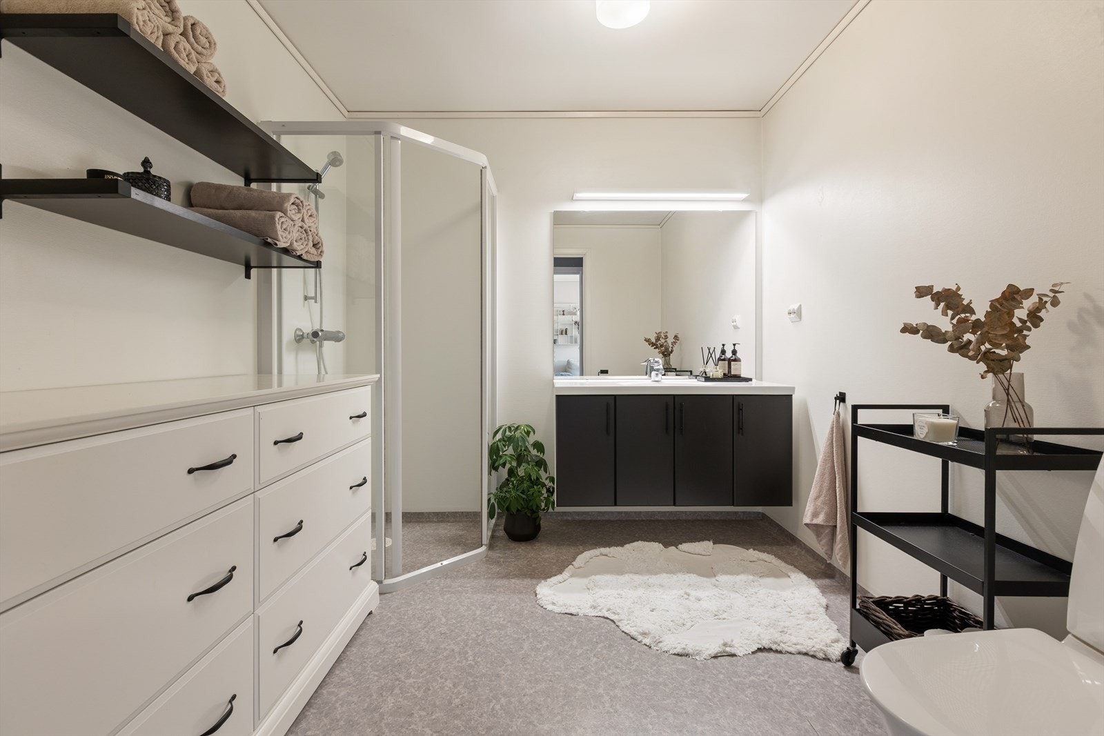 Svært romslig baderom i 1.etasje, utstyrt med servant med baderomsmøbel, speil med belysning og dusjhjørne. Galleribilde