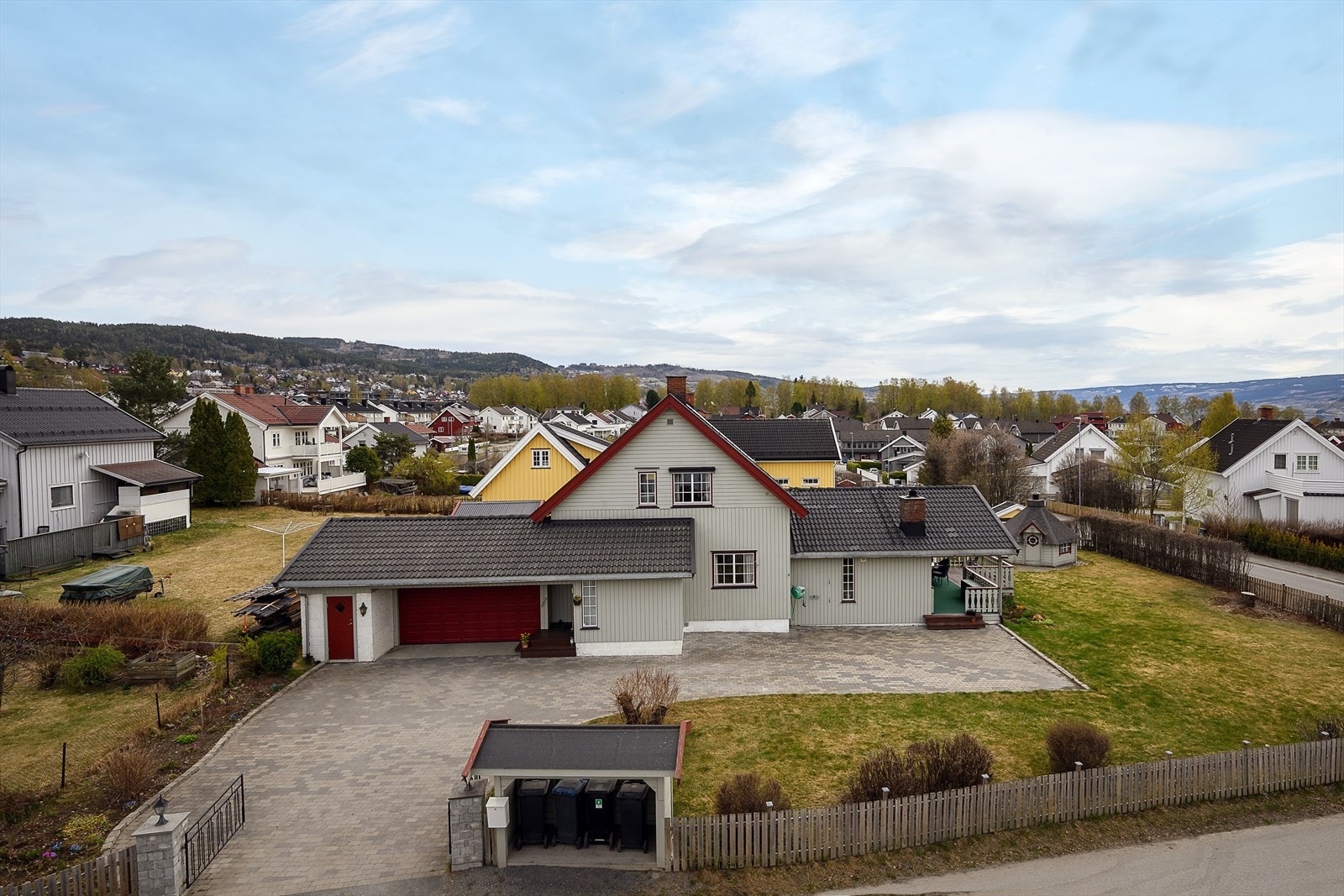 Tomten er pent opparbeidet med plen, beplantning og steinlagt gårdsplass. Galleribilde