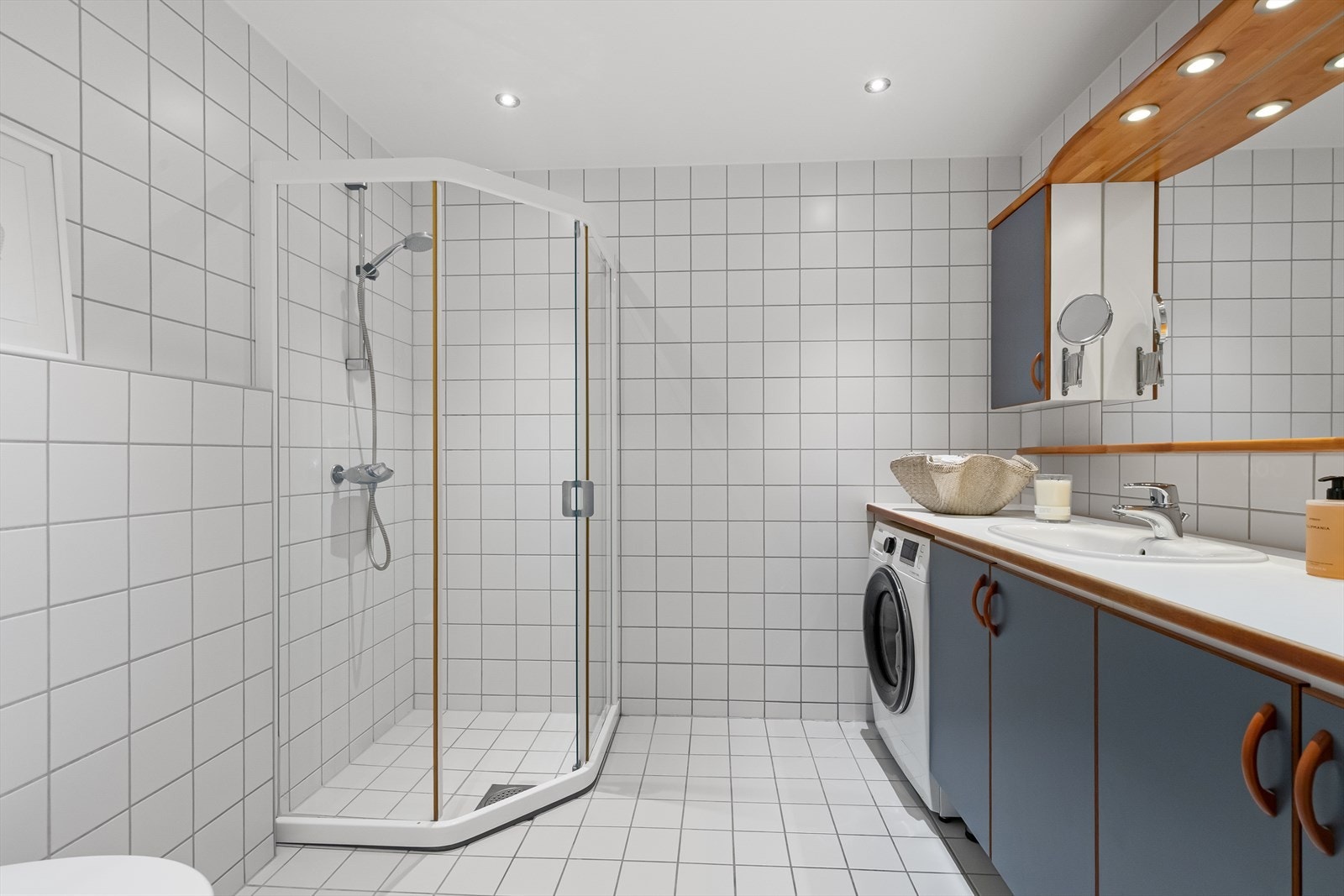 Romslig bad med dusjnisje, servant med underskap, speil, skap og wc. Galleribilde