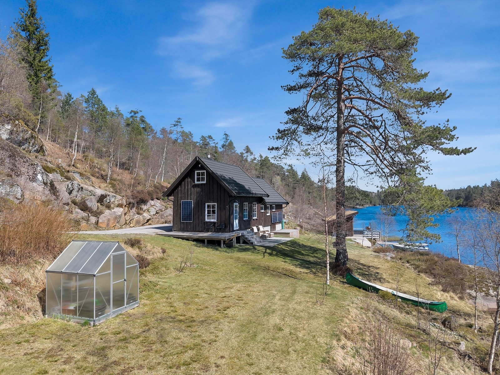 Eiendommen ligger usjenert til i skrånende terreng ned mot vannet, med gruset innkjørsel. Galleribilde