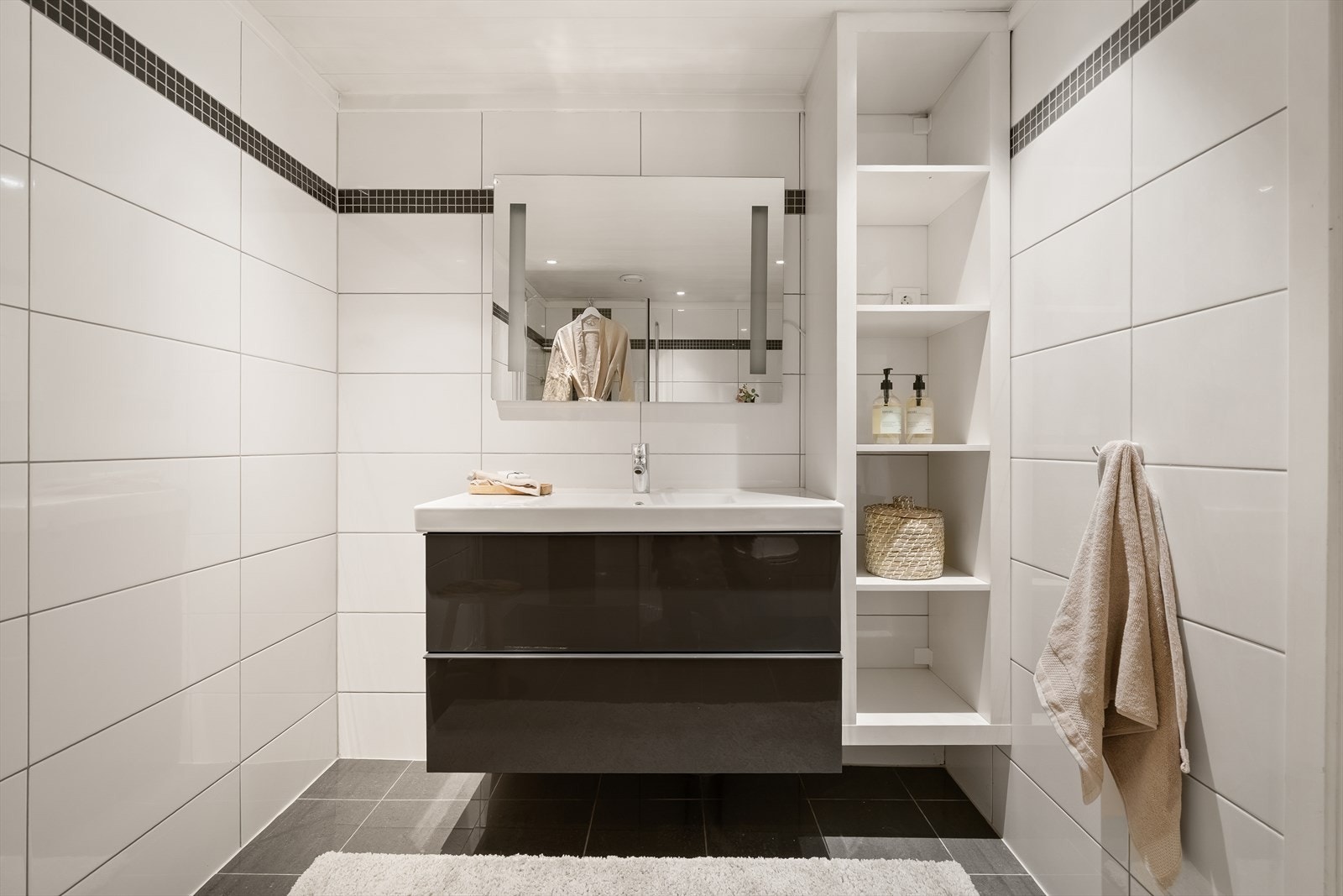 Badet er innredet med en moderne servant med skuffer og integrerte hyller for oppbevaring. Galleribilde
