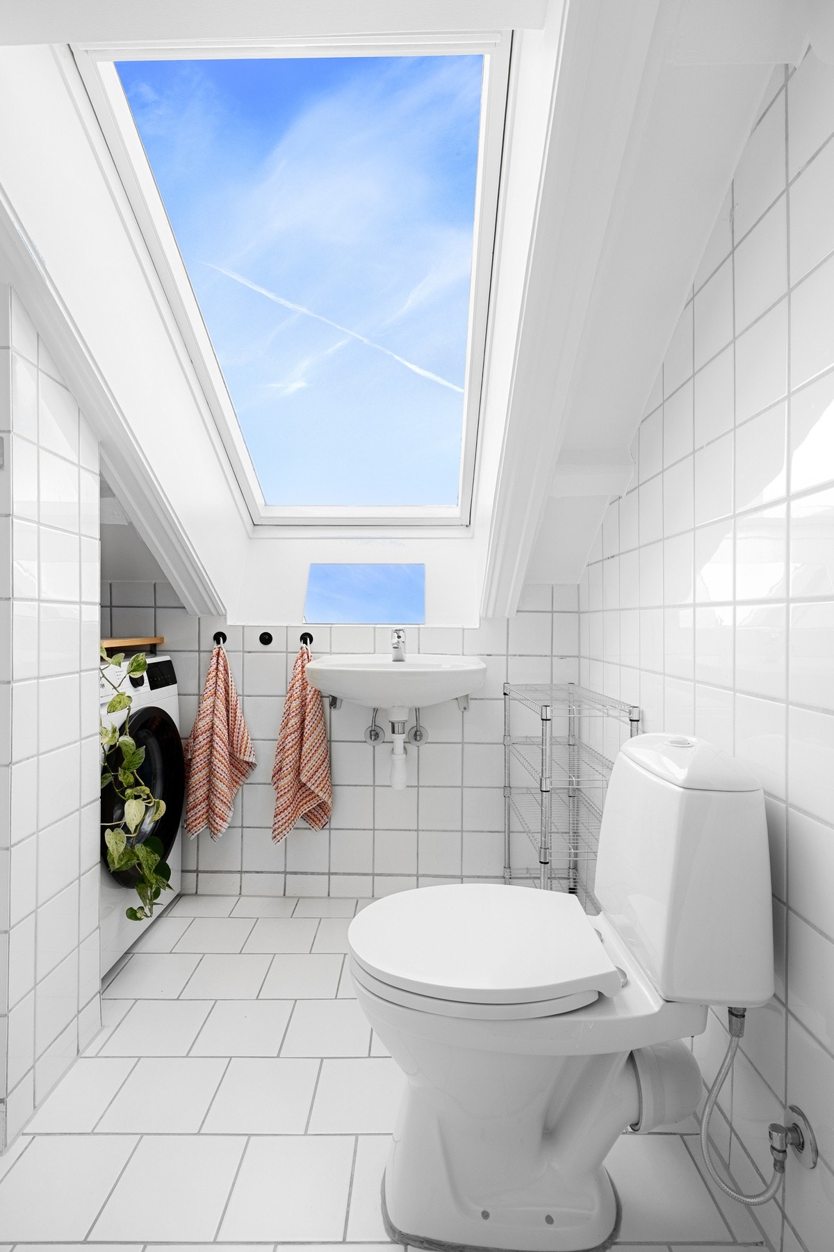 Lyst bad med fliser på vegger og gulv. Det hyggelige vinduet i taket sørger for gode lysforhold på badet. Galleribilde