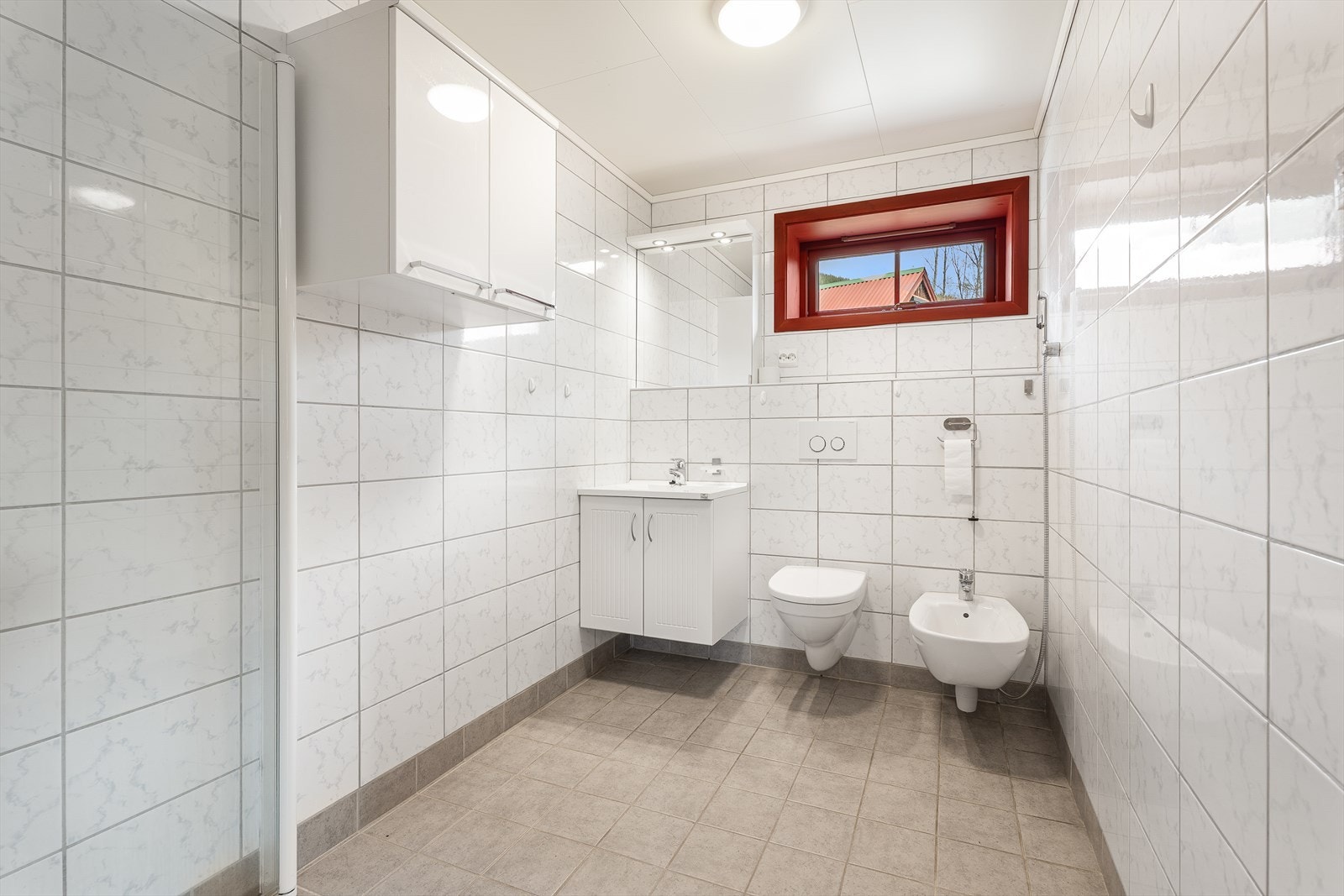 Her har du et stort og lyst flislagt bad, som fremstår moderne og innbydende. Galleribilde