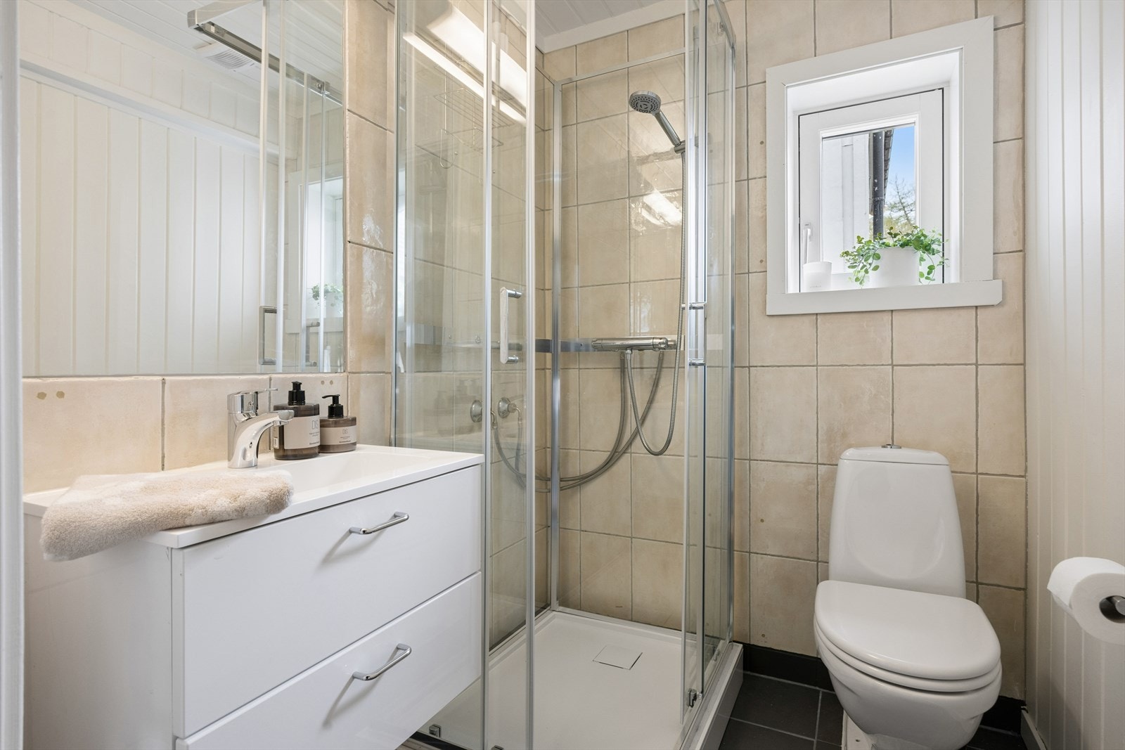 Baderommet er av eldre dato, men er modernisert med nye fliser på gulvet i 2026. Badet er ellers utstyrt med dusjkabinett, toalett og baderomsinnredning med nedfelt servant. Galleribilde