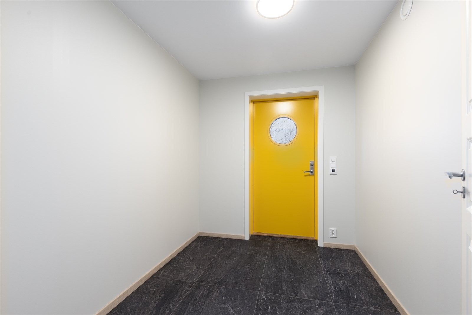 Entreen har praktiske flis på gulv med varmekabler. Den flotte gule inngangsdøren gir boligen et lekkert blikkfang. Galleribilde