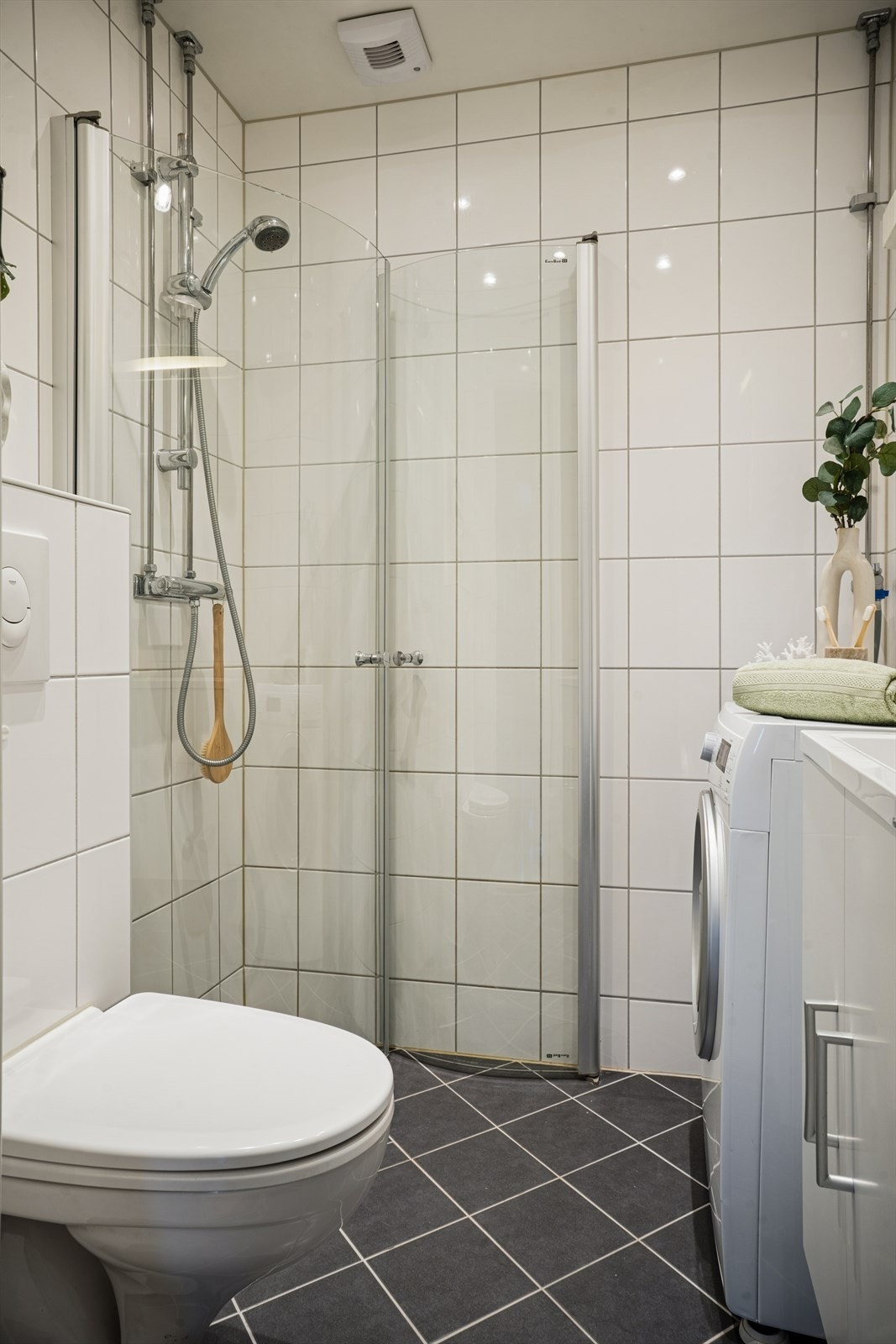 Lyst og moderne baderom med elegante materialvalg. Baderommet har alt du har behov for; dusjhjørne, toalett, servant med underskap og opplegg til vaskemaskin. Galleribilde