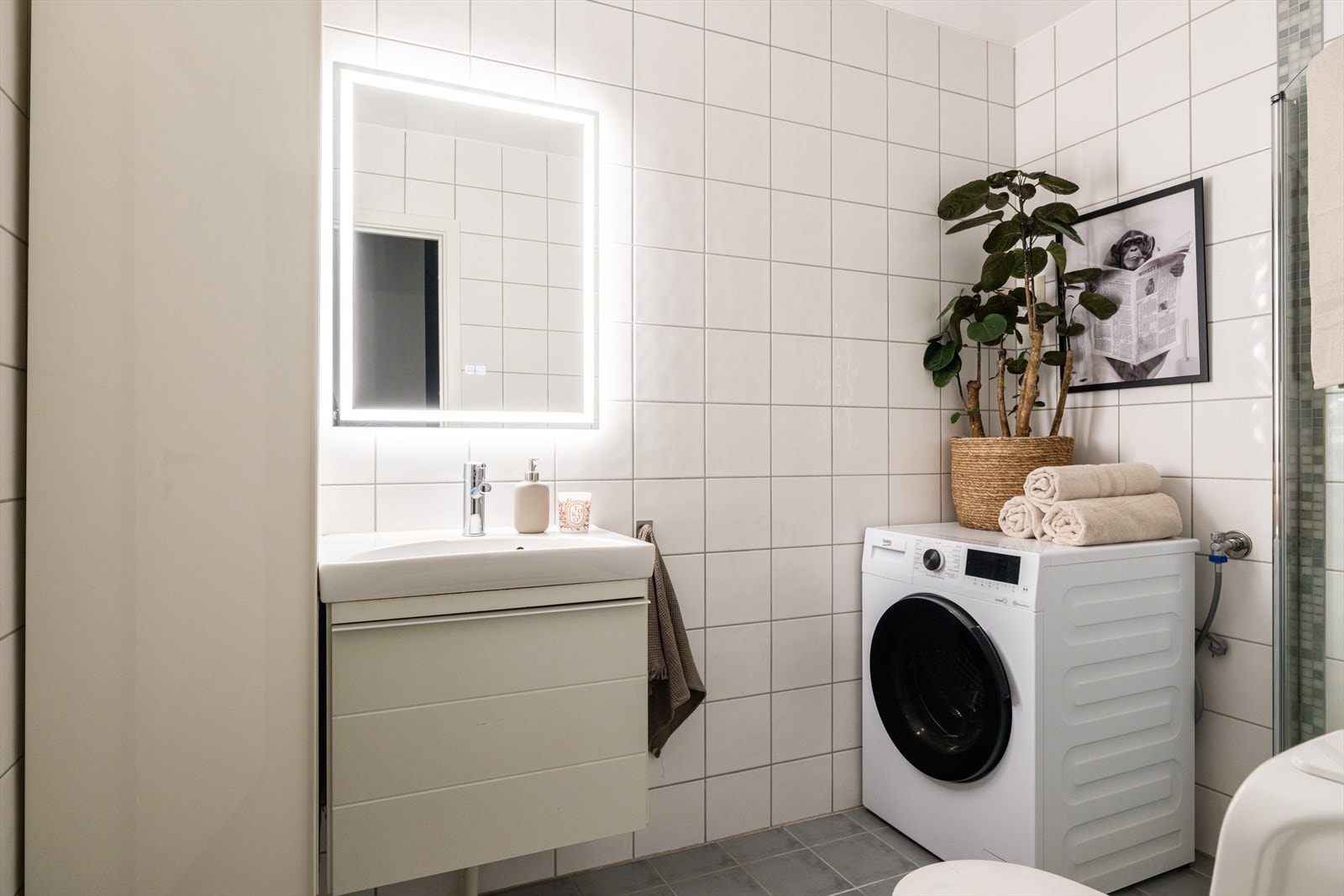 Lyst flislagt bad med gulvvarme og opplegg for vaskemaskin. Galleribilde