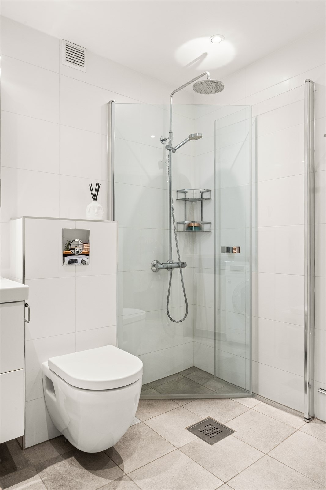 Badet er innredet med vegghengt toalett, servant nedfelt i baderomsinnredning og dusjhjørne med svingbare glassdører. Galleribilde