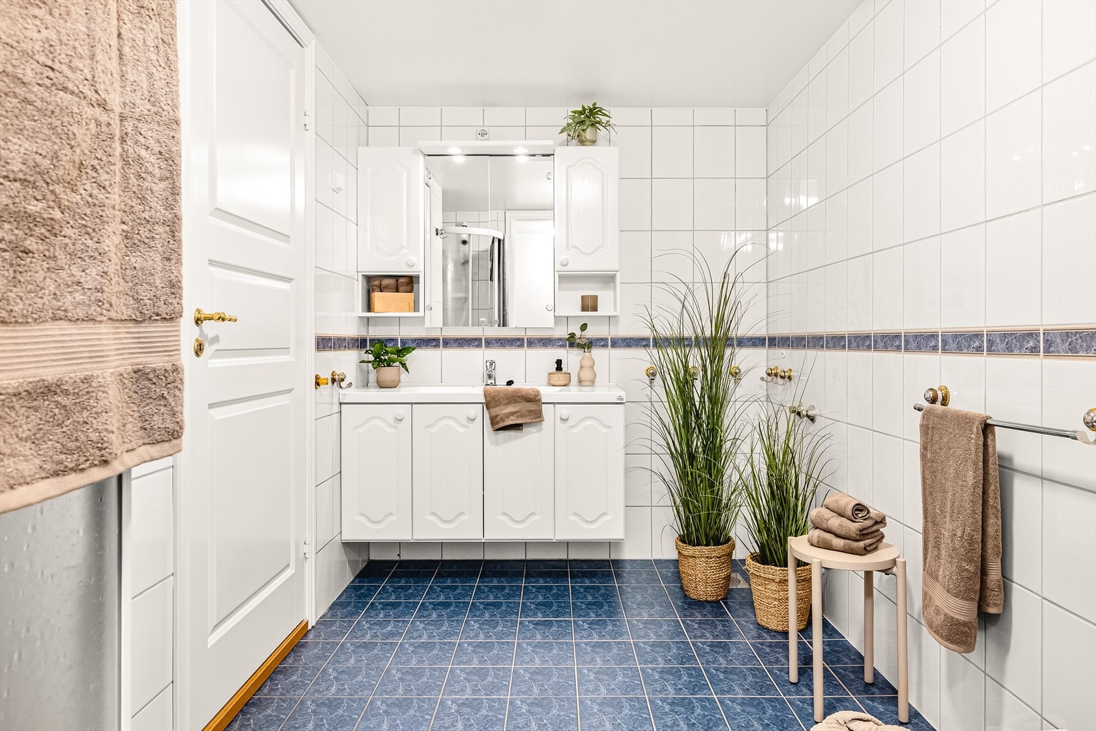 Badet er flislagt og utstyrt med gulvvarme, baderomsmøbel med heldekkende servant og speilskap med belysning. Galleribilde