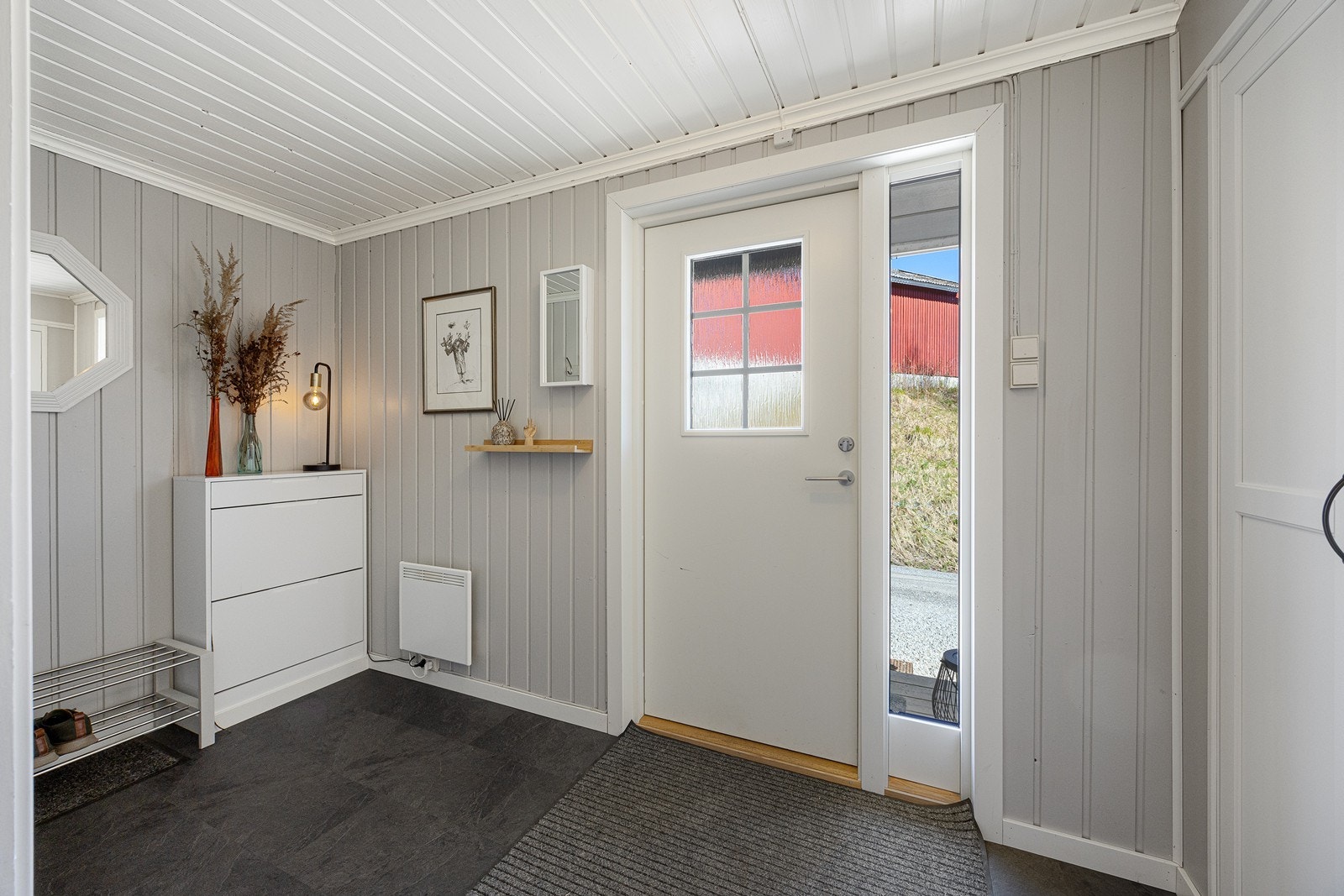 Vel inne blir vi ønsket velkommen i en fin entré med lysmalt panel på veggene og grått flislaminat på gulvet. Galleribilde