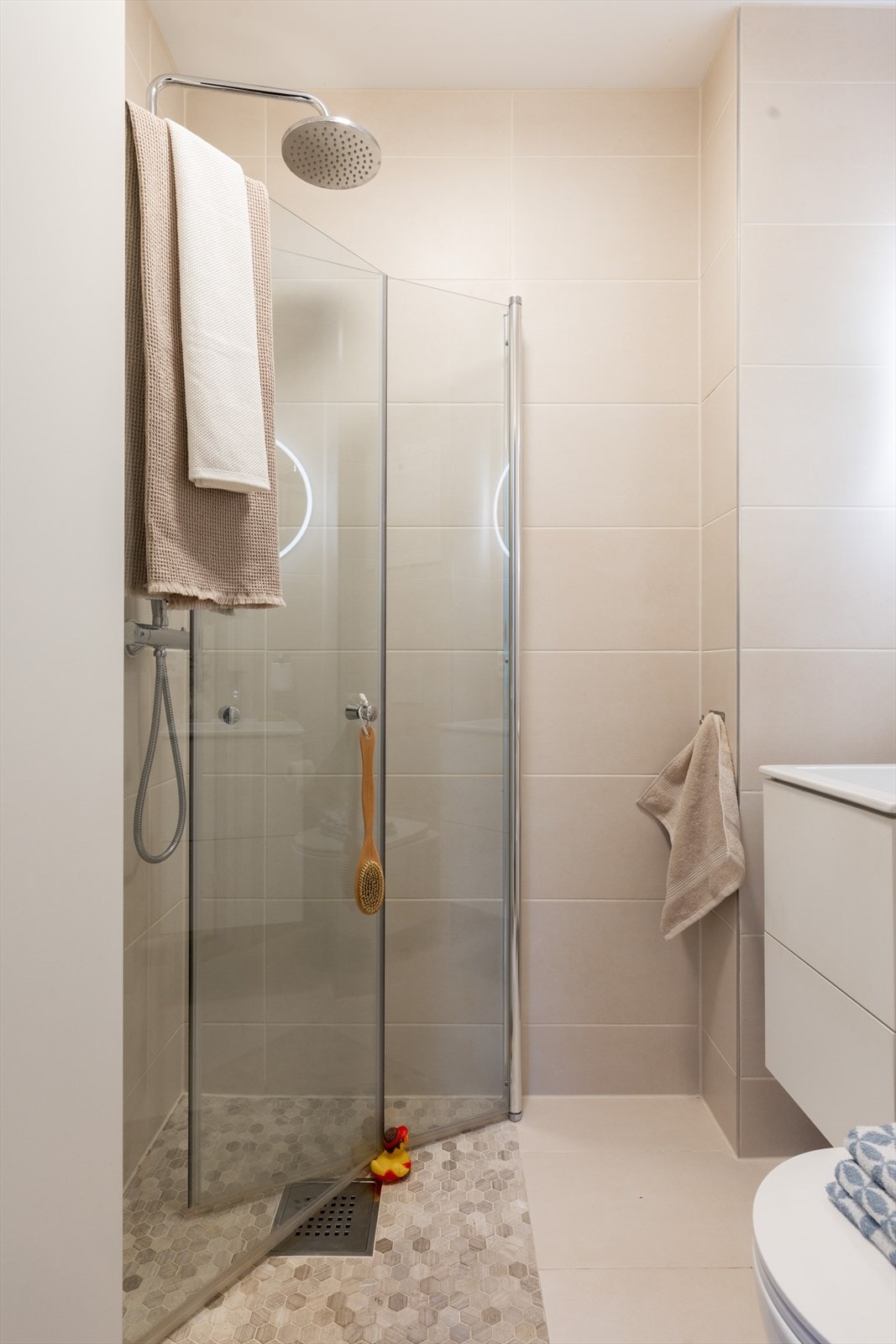 Badet er innredet med servant med skuffer, speil med belysning, vegghengt toalett og dusjhjørne med innfellbare dusjdører. Galleribilde