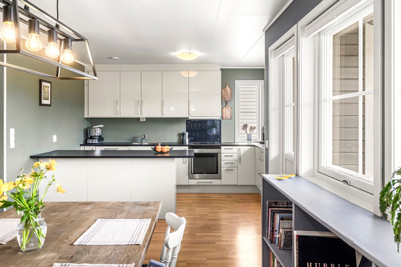 Kjøkken med nyere oppvaskmaskin og komfyr utstyrt med slette fronter, laminert benkeplate, integrert komfyr, platetopp, oppvaskmaskin og frittstående kjøl/fryseskap. Galleribilde
