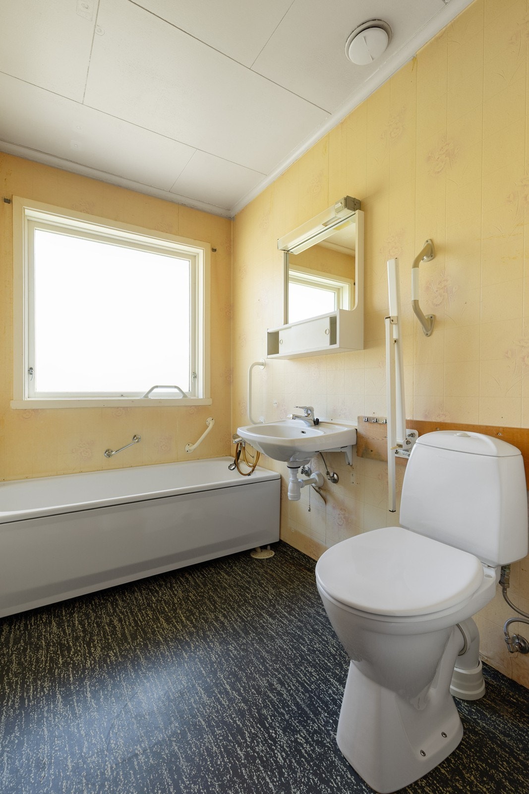 Badet er belagt med belegg på gulv og våtromstapet på vegger Galleribilde
