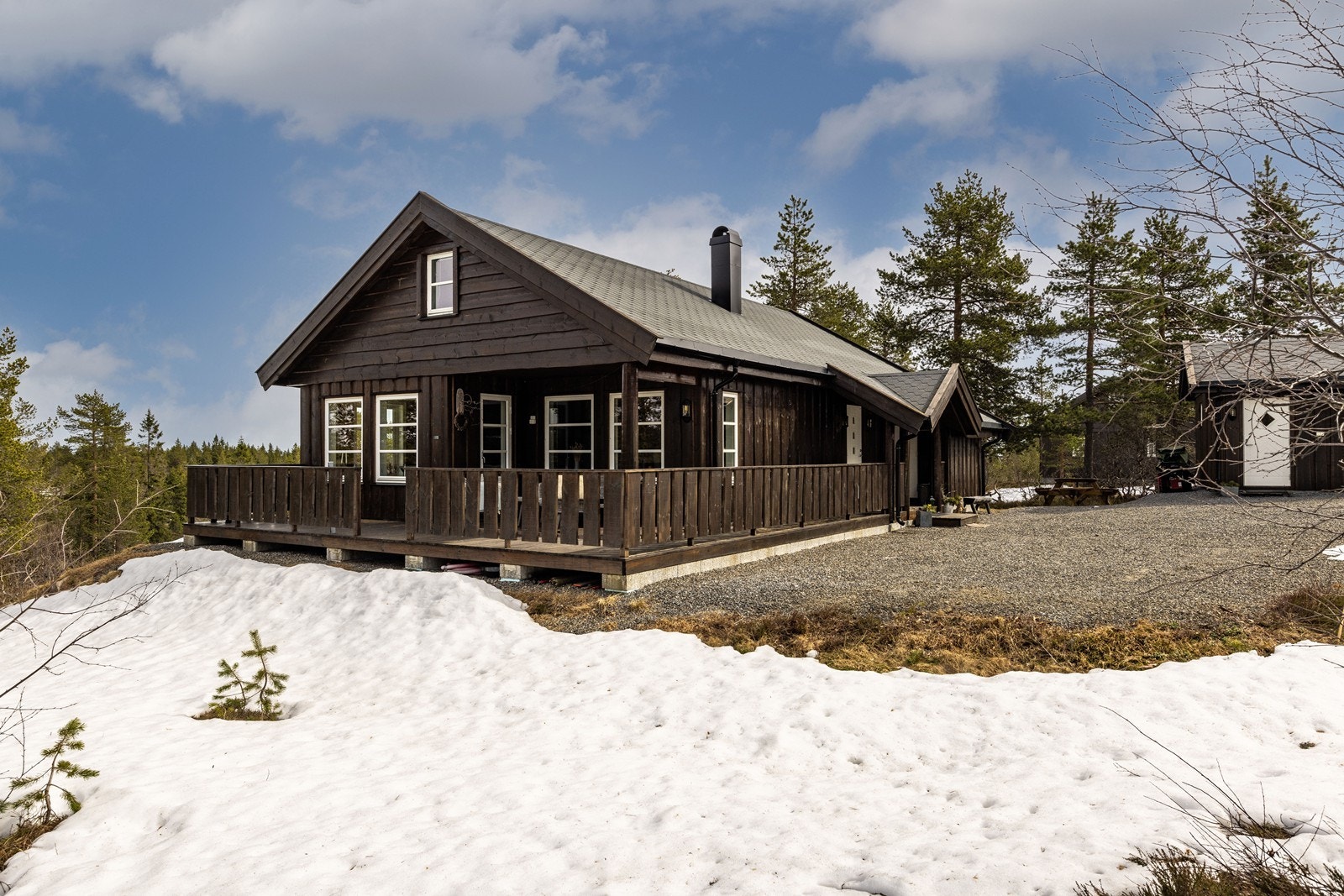 Hytta har en gjennomført stil med stående villmarkskledning og tak tekket med pappshingel. Galleribilde