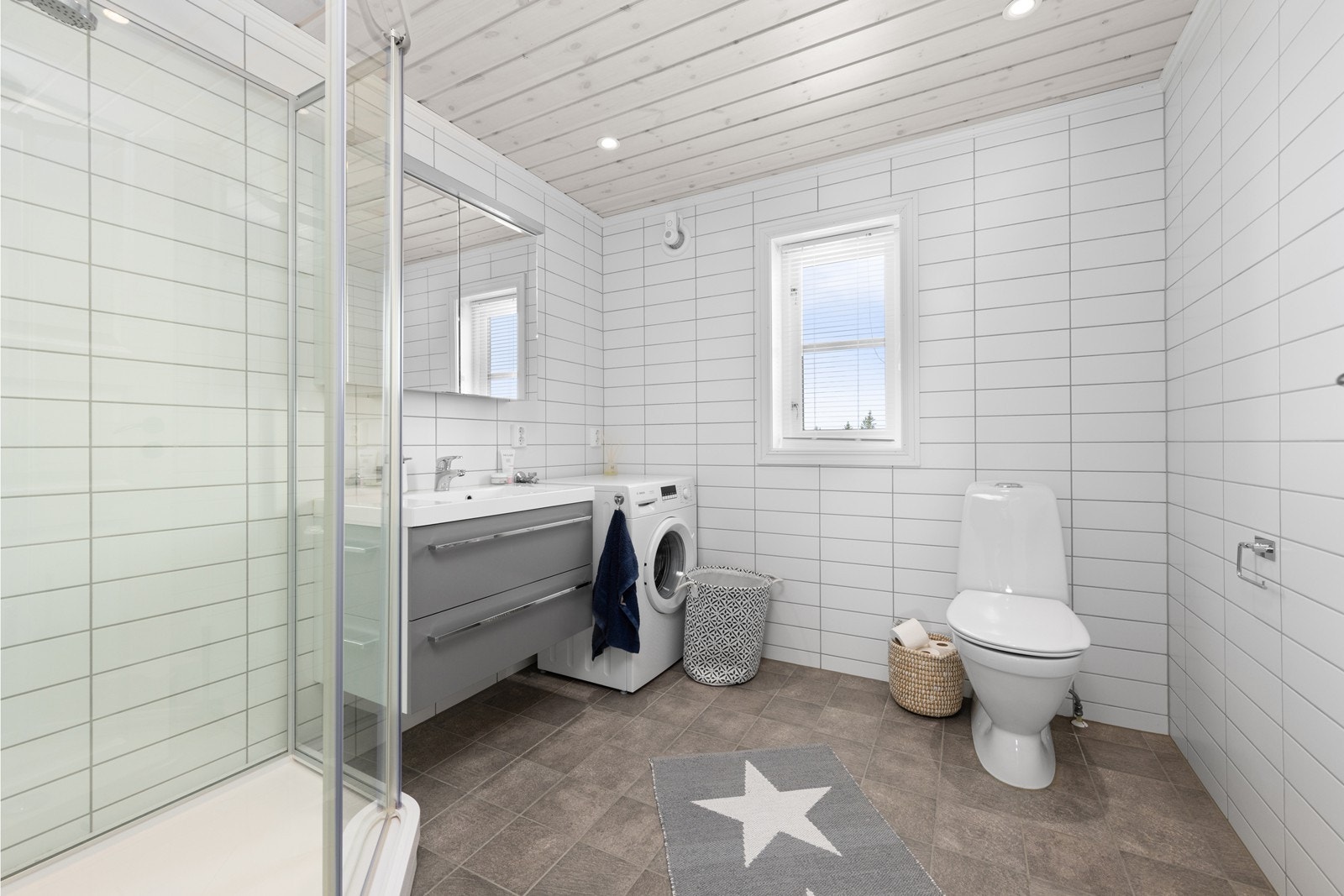 Badet er praktisk innredet med dusjkabinett, servantinnredning og opplegg for vaskemaskin. Galleribilde