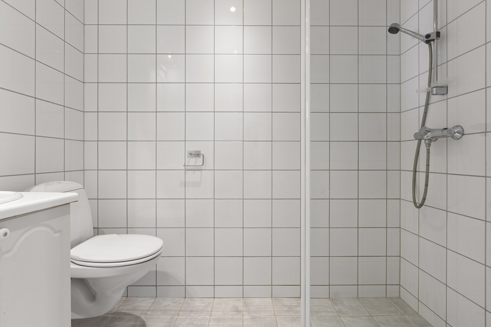 Badet er flislagt og har gulvvarme. Rommet har en innredning bestående av nedfelt servant på skapløsning og et pent speil med belysning i overkant. Galleribilde