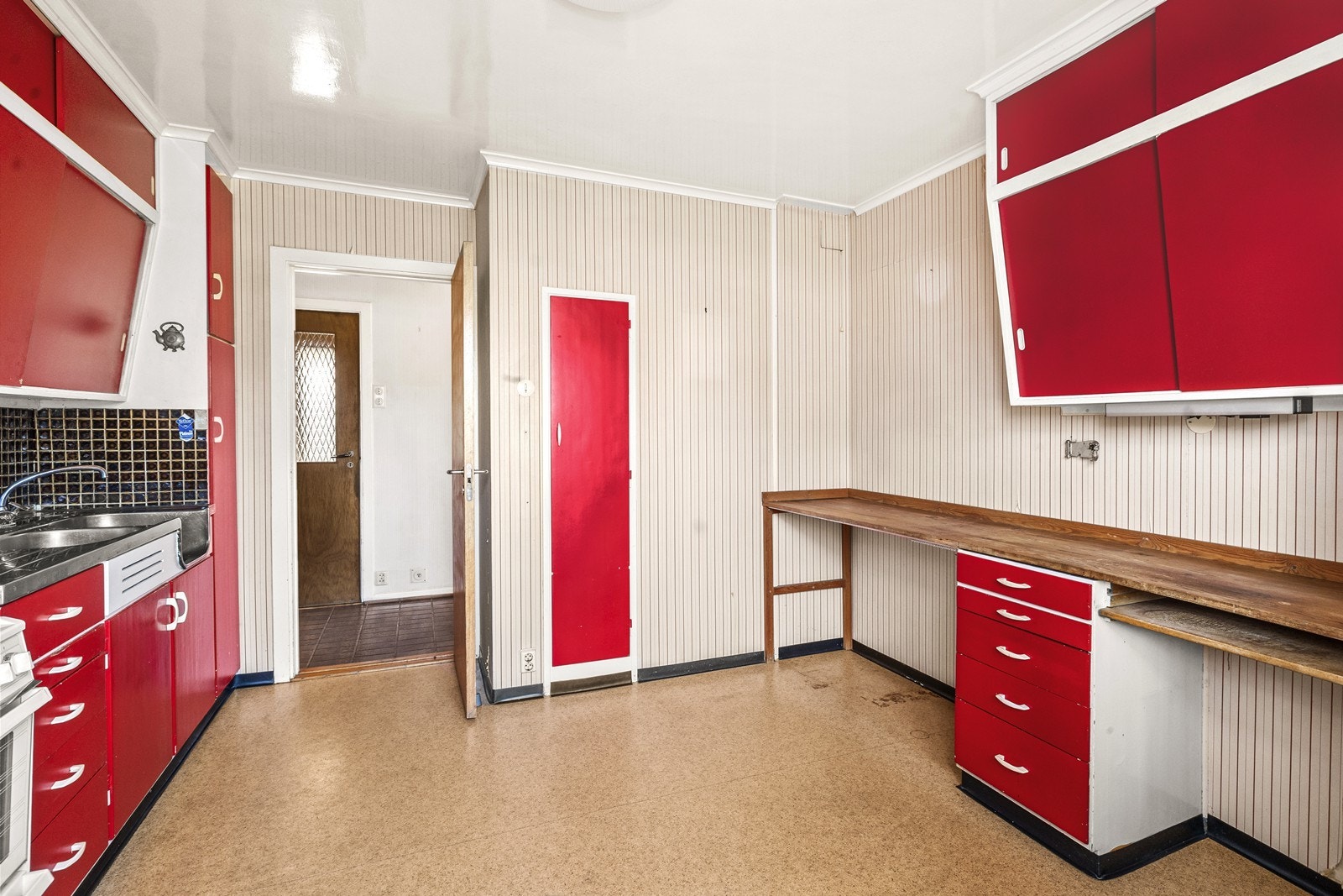 Kjøkkenet har en praktisk løsning med benkeplate i børstet stål med dobbel vaskekum og opplegg for komfyr og kjøleskap. Galleribilde