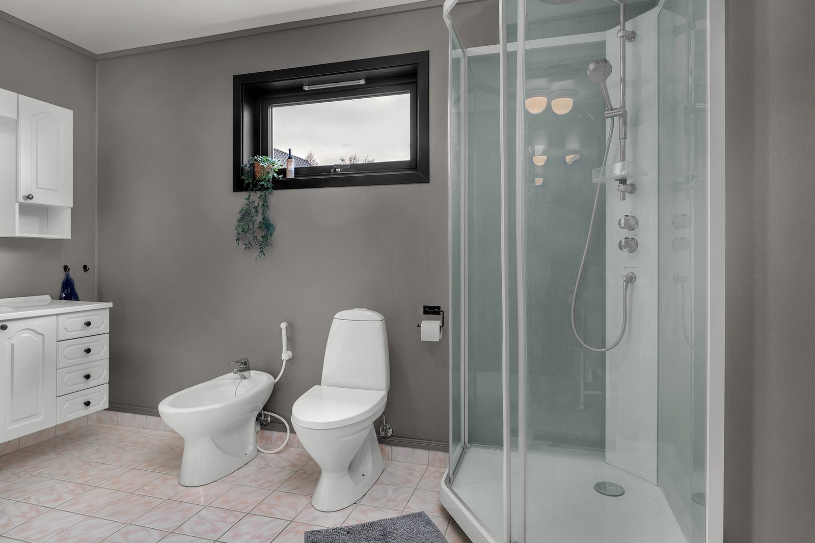 Badet har innredning med dobbel servant, toalett, dusjkabinett og bidet Galleribilde