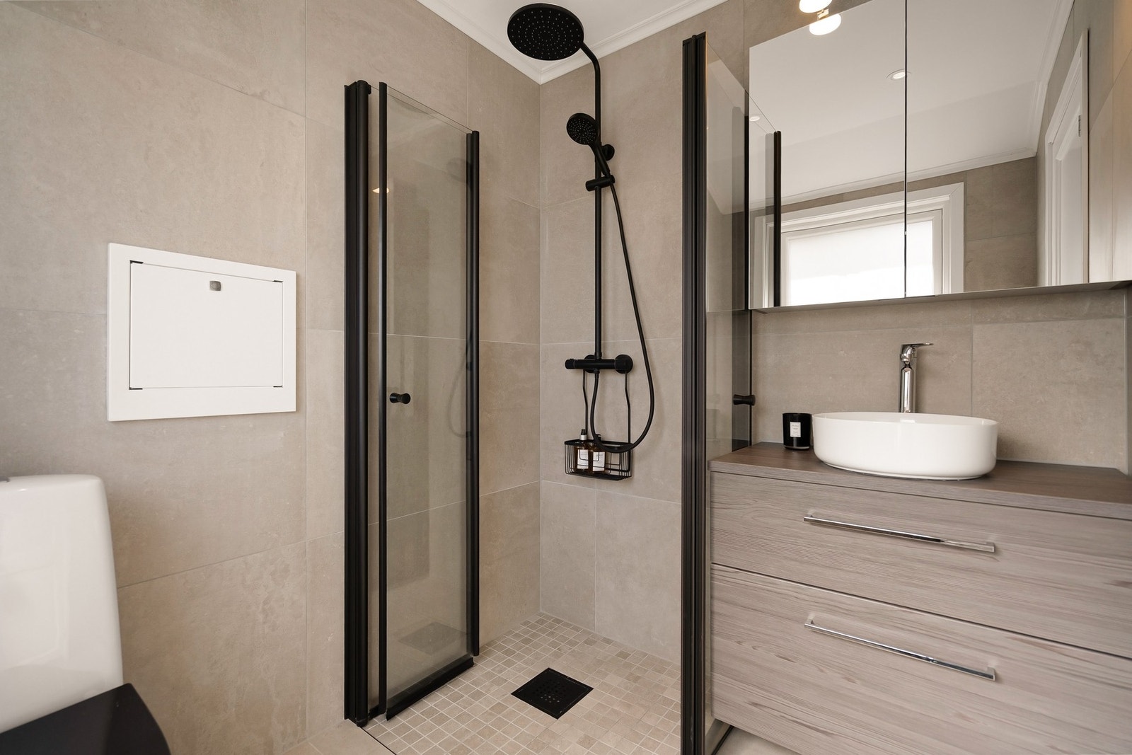 Badet er flislagt med innfelt downlights, elektrisk gulvvarme, klosett, servantinnredning, speilskap m/lys og dusjhjørne med svingbare glassdører. Galleribilde
