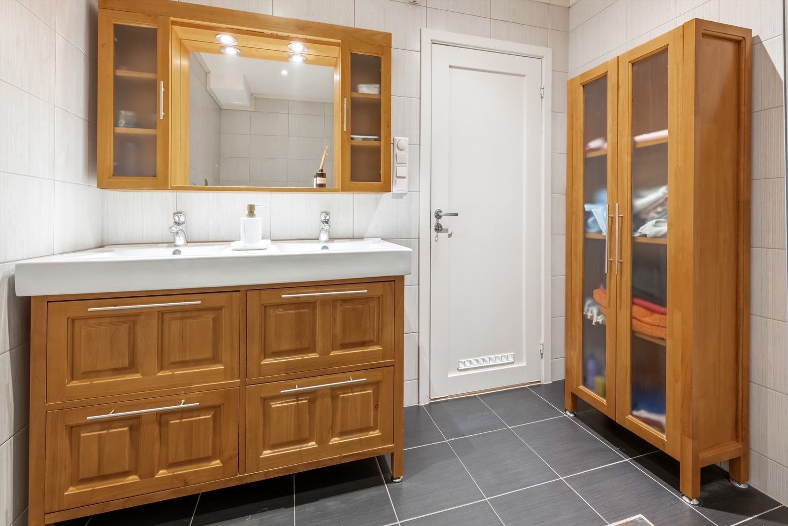 Badet er innredet med blant annet gulvstående toalett, dusjkabinett samt baderomsinnredning med to nedfelte servanter. Galleribilde