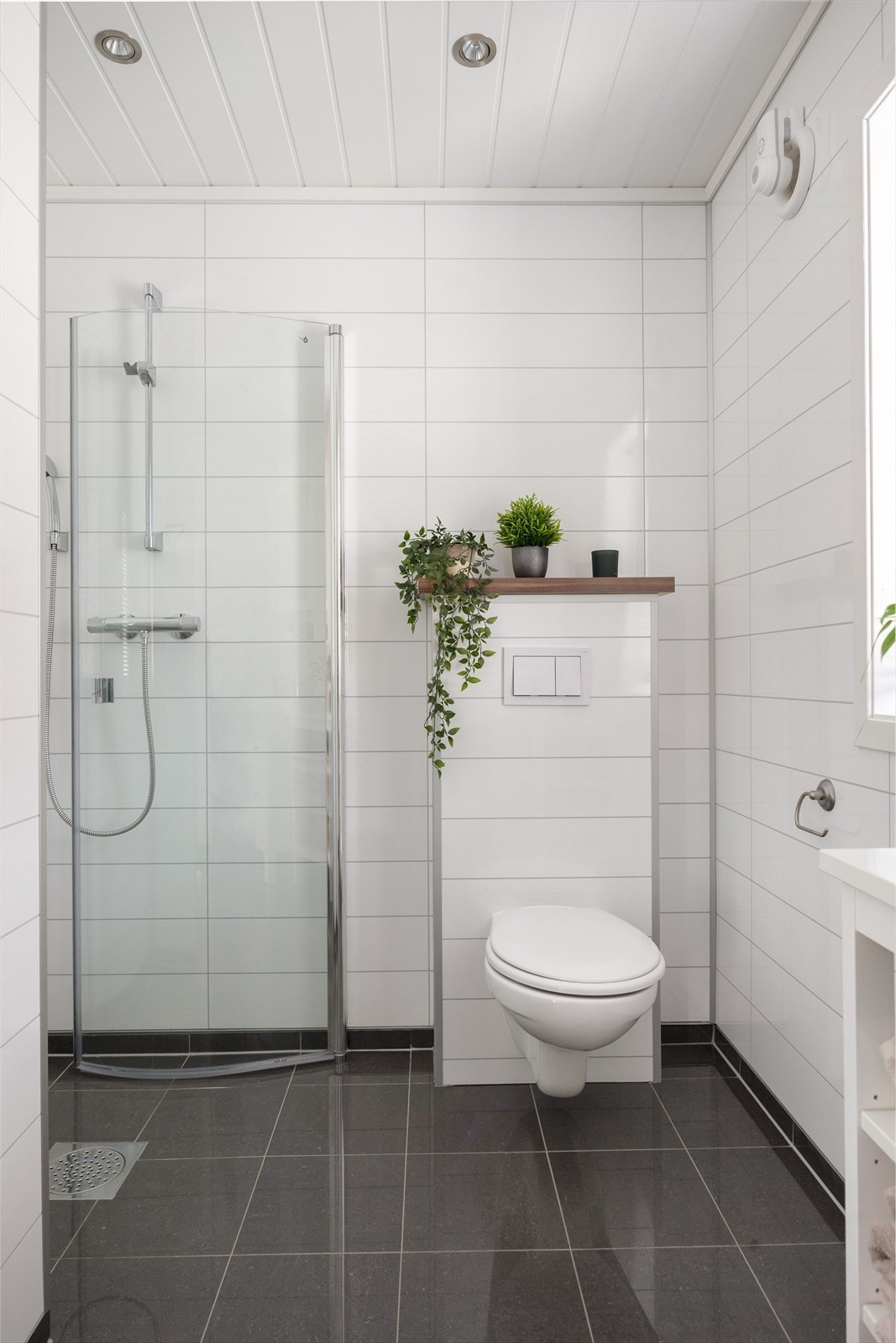Badet har flislagt gulv, våtromsplater på veggene og et praktisk dusjhjørne. Galleribilde