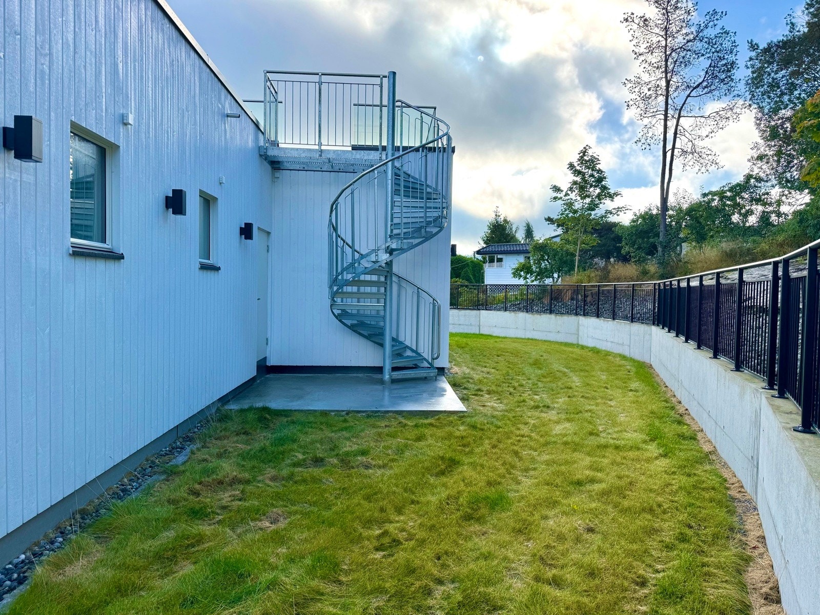 Utgang fra stuen til platting og hage med vindeltrapp til takterrassen Galleribilde