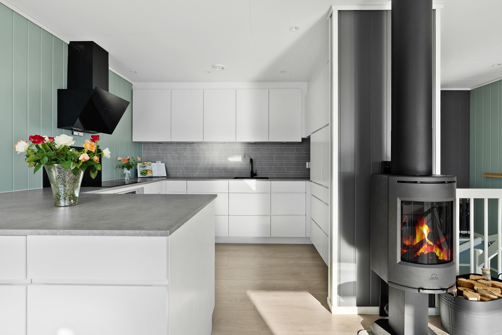 Kjøkkeninnredningen fra Kvikk har glatte fronter og en funksjonell utforming. Peisovnen gir ekstra varme og hygge på kjølige dager. Galleribilde