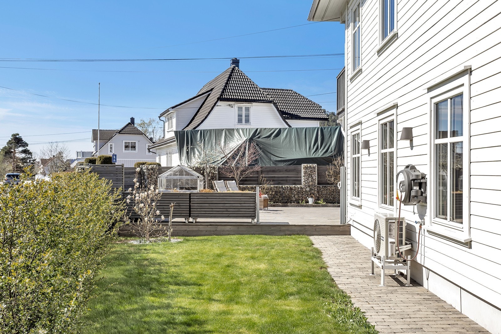 Eiendommen har en flat tomt med plen og steinlagte gangveier, noe som gir et praktisk og velstelt uteområde. Galleribilde