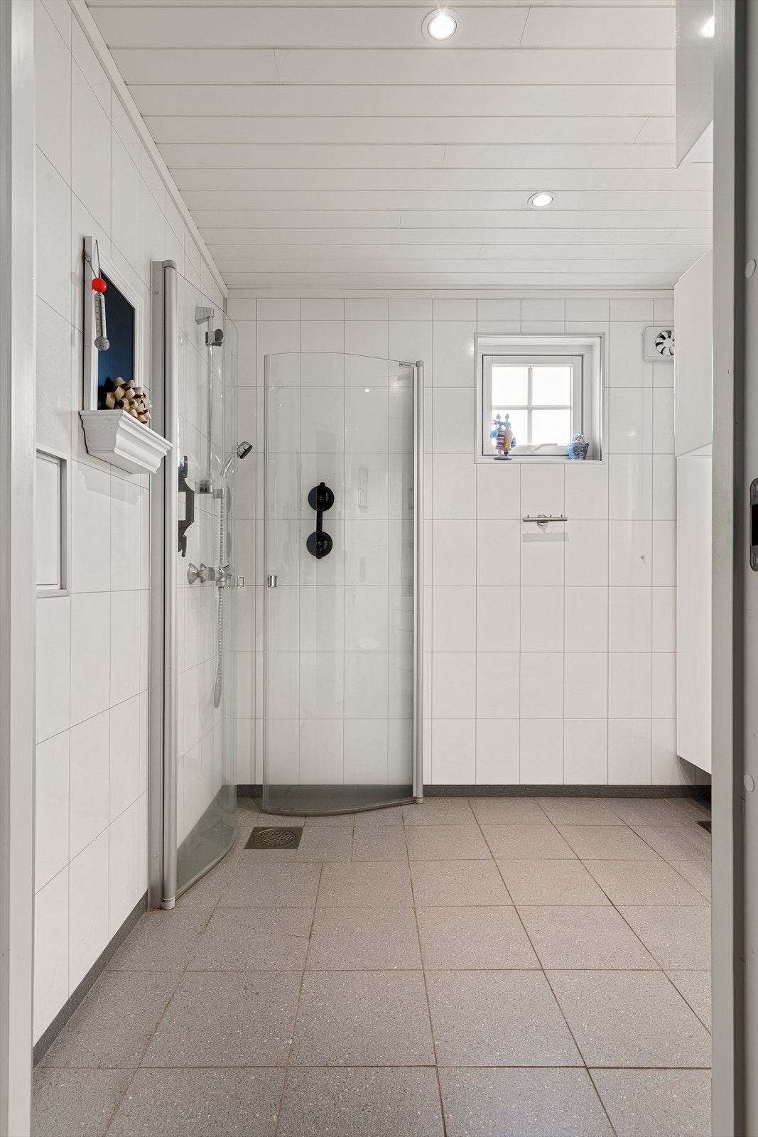 Badet har baderomsplater på veggene, flislagt gulv og malt panel i himlingen Galleribilde