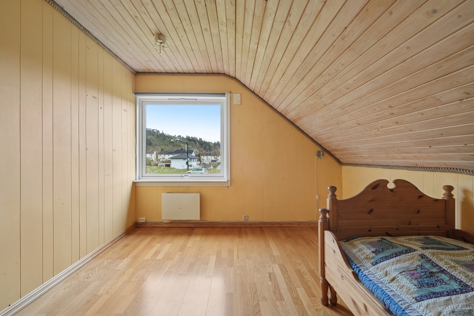 Soverom med skråtak, med parkett på gulvet og panel på vegger og i himling. Galleribilde