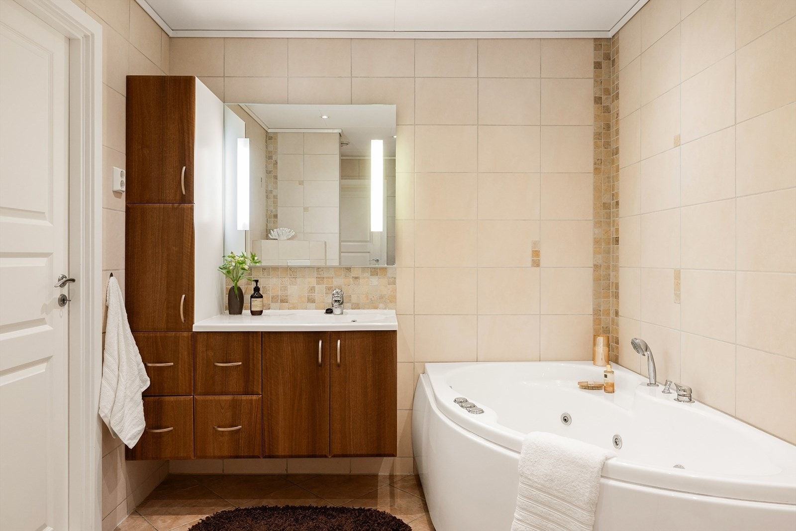 Badet er innredet med servant med oppbevaring, vegghent toalett, dusjkabinett og badekar. Galleribilde