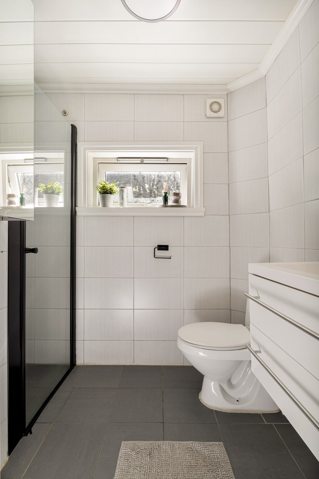Badet er helfliset og utstyrt med toalett, dusjhjørne og baderomsmøbelement med nedfelt porselen vask. Badet måler 3 kvm. Galleribilde