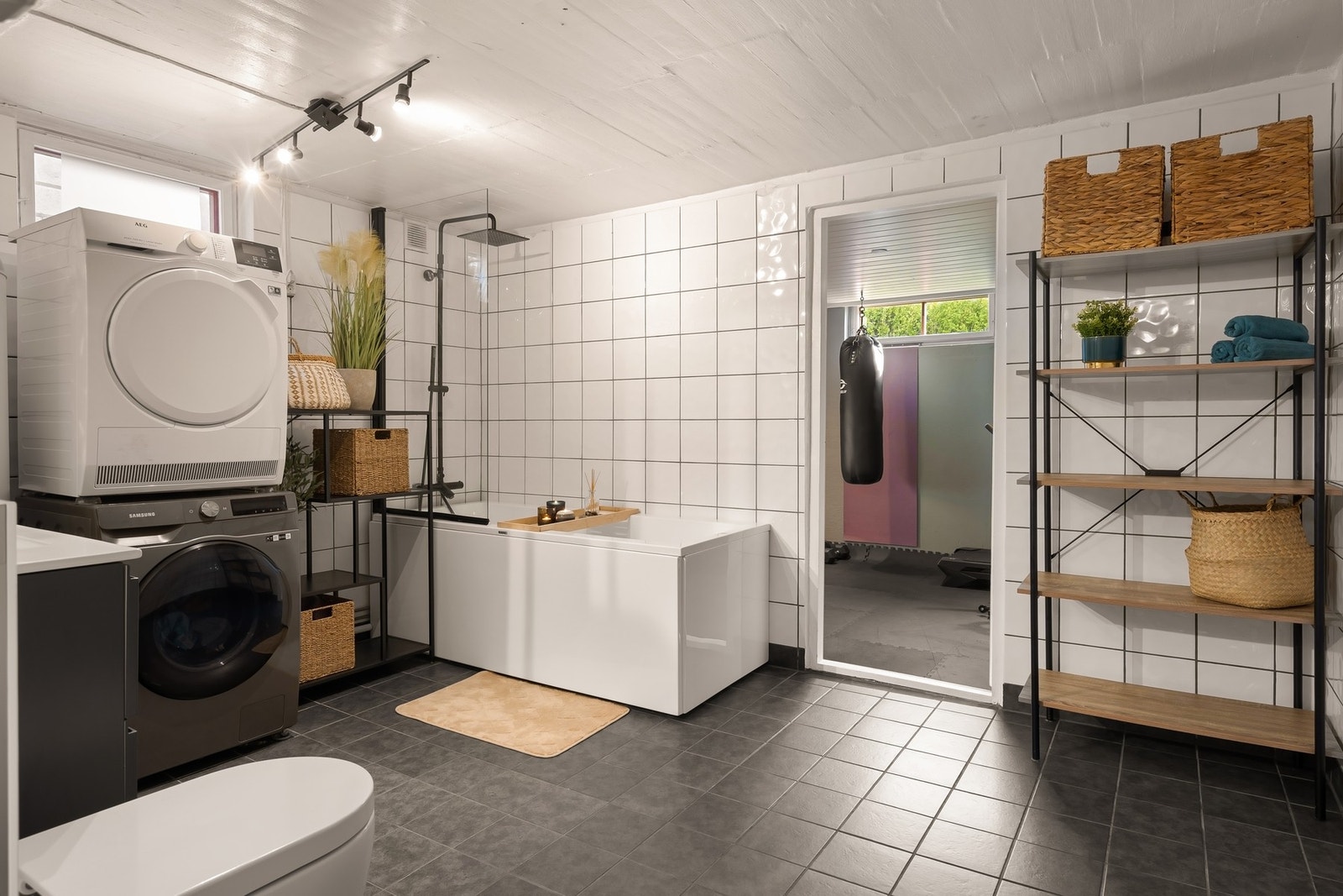Bad/vaskerom med baderomsinnredning, badekar, vegghengt klosett og uttak for vaskemaskin. Galleribilde