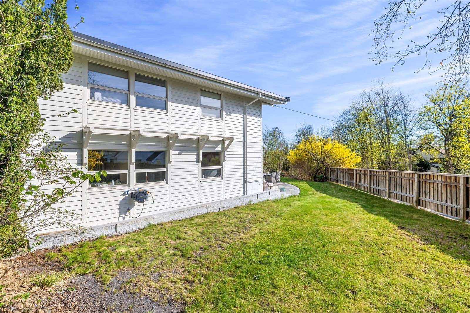 På siden av huset er en romslig og skjermet gressplen- perfekt for lek og eventuelt en trampolineplass. Galleribilde