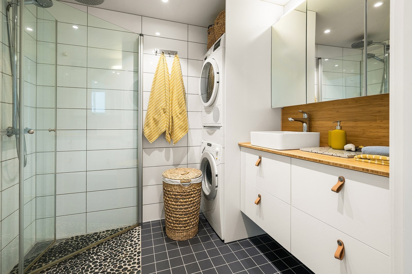 Badet består av dusjhjørne, benkeplate i tre med servant, vegghengt wc og opplegg for vaskemaskin. Galleribilde