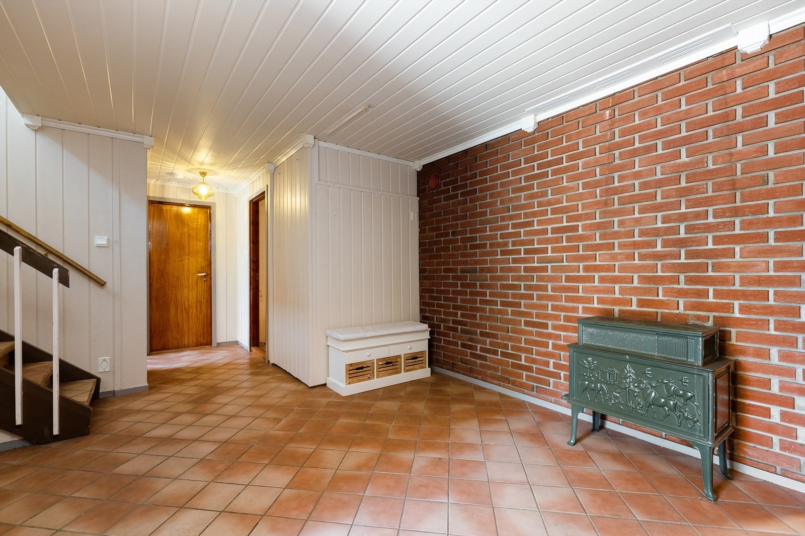 Hallen i underetasjen har en eksponert teglsteinsvegg og en vedovn som gir ekstra varme. Galleribilde