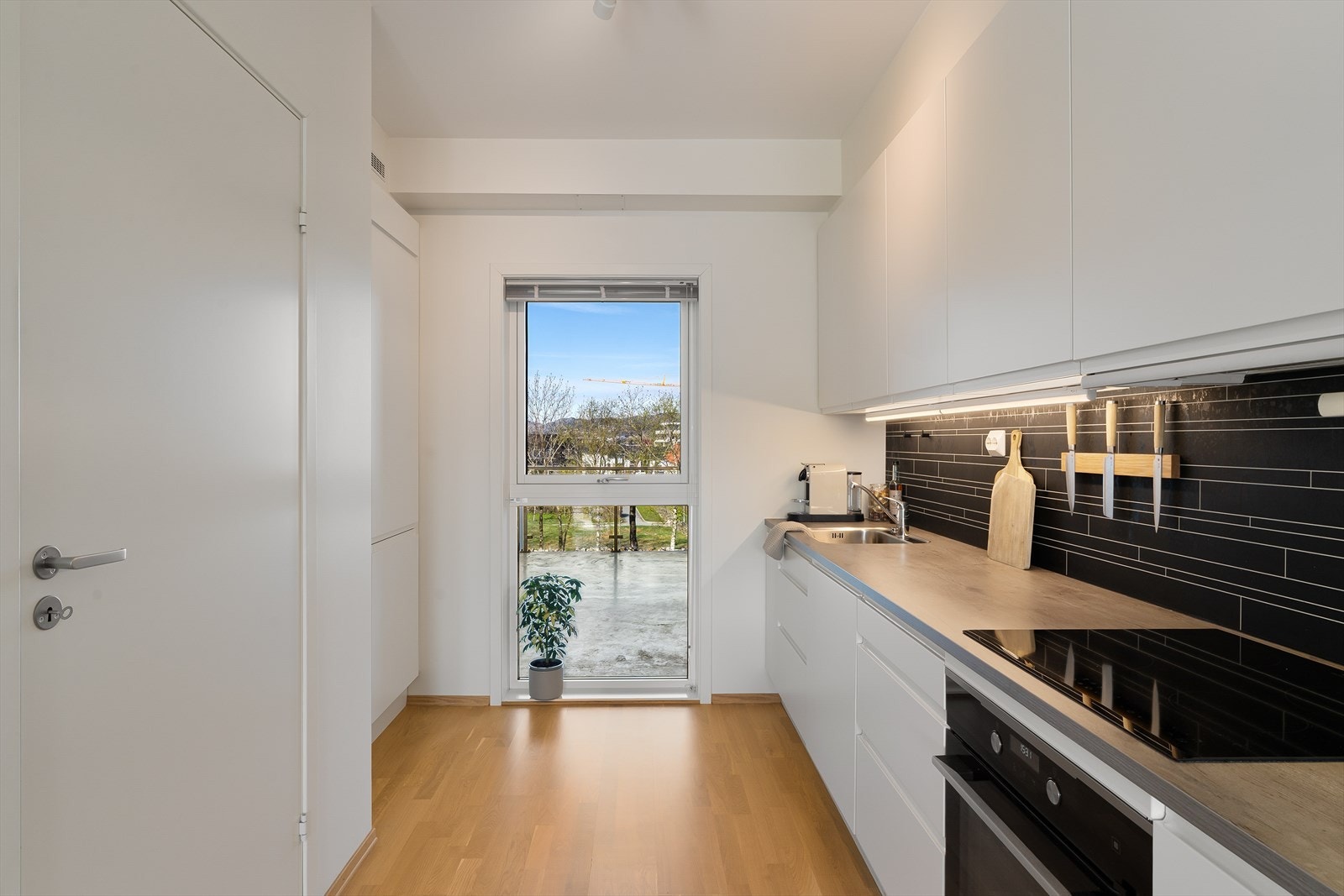 Flott kjøkken med pen kjøkkeninnredning med hvite glatte fronter og en benkeplate av laminat. Galleribilde