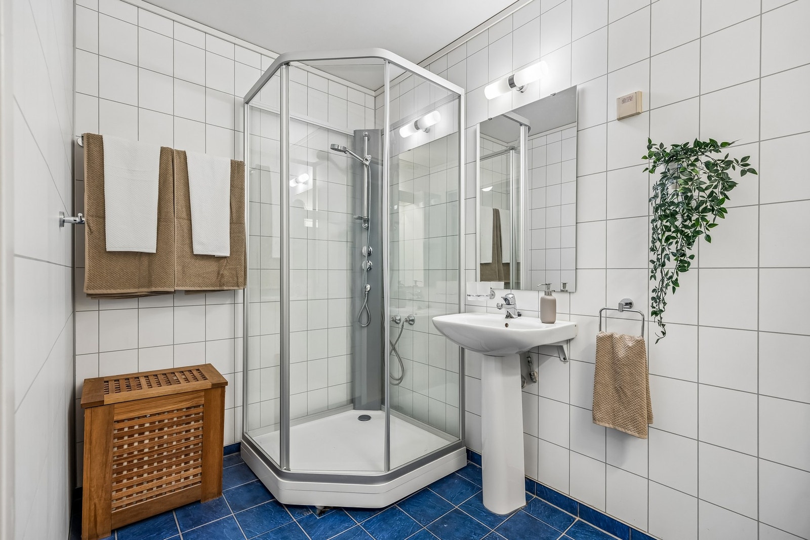 Badet er innredet med servant, speil med overlys, vegghengt baderomsmøbel og dusjkabinett. Galleribilde