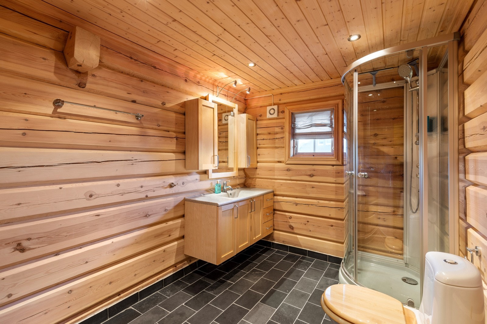 Badet har flislagt gulvoverflate med gulvvarme, og det er montert baderomsinnredning, wc og dusjkabinett Galleribilde