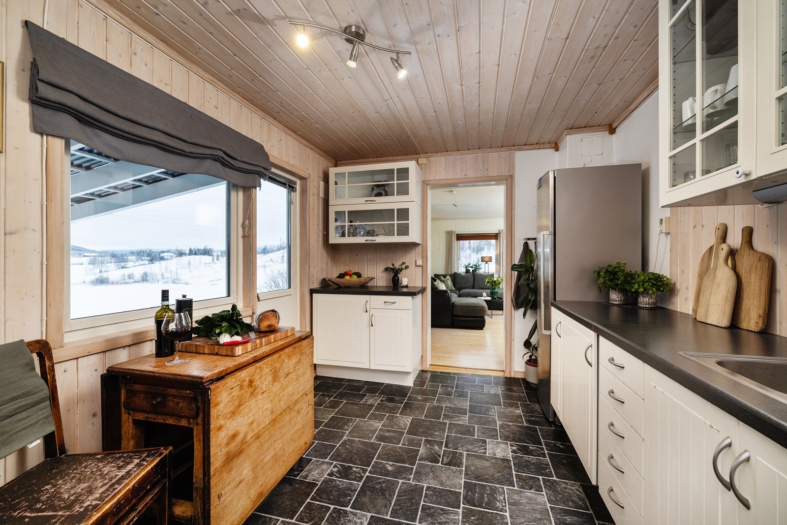 Kjøkkenet er et eget, lukket rom med innredning langs én vegg og plass til en liten spiseplass ved vinduet. Galleribilde