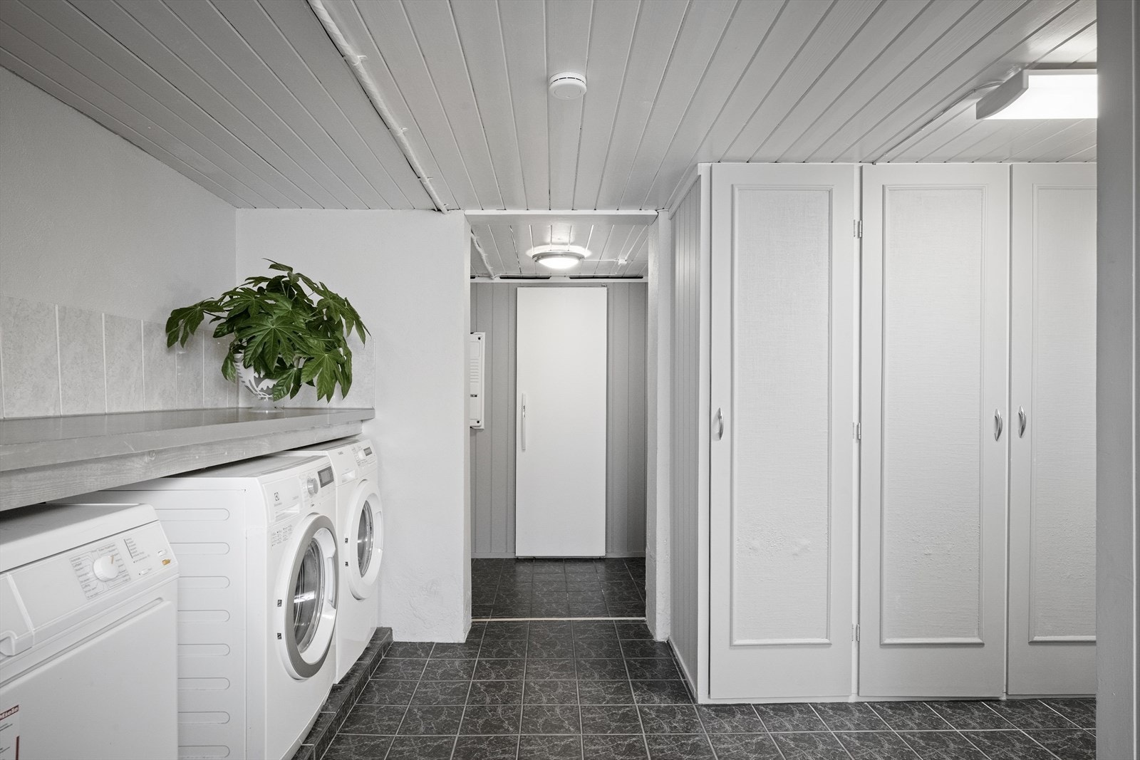 Flislagt gulv og gode arbeidsflater tilknyttet vaskemaskin og tørketrommel. Galleribilde