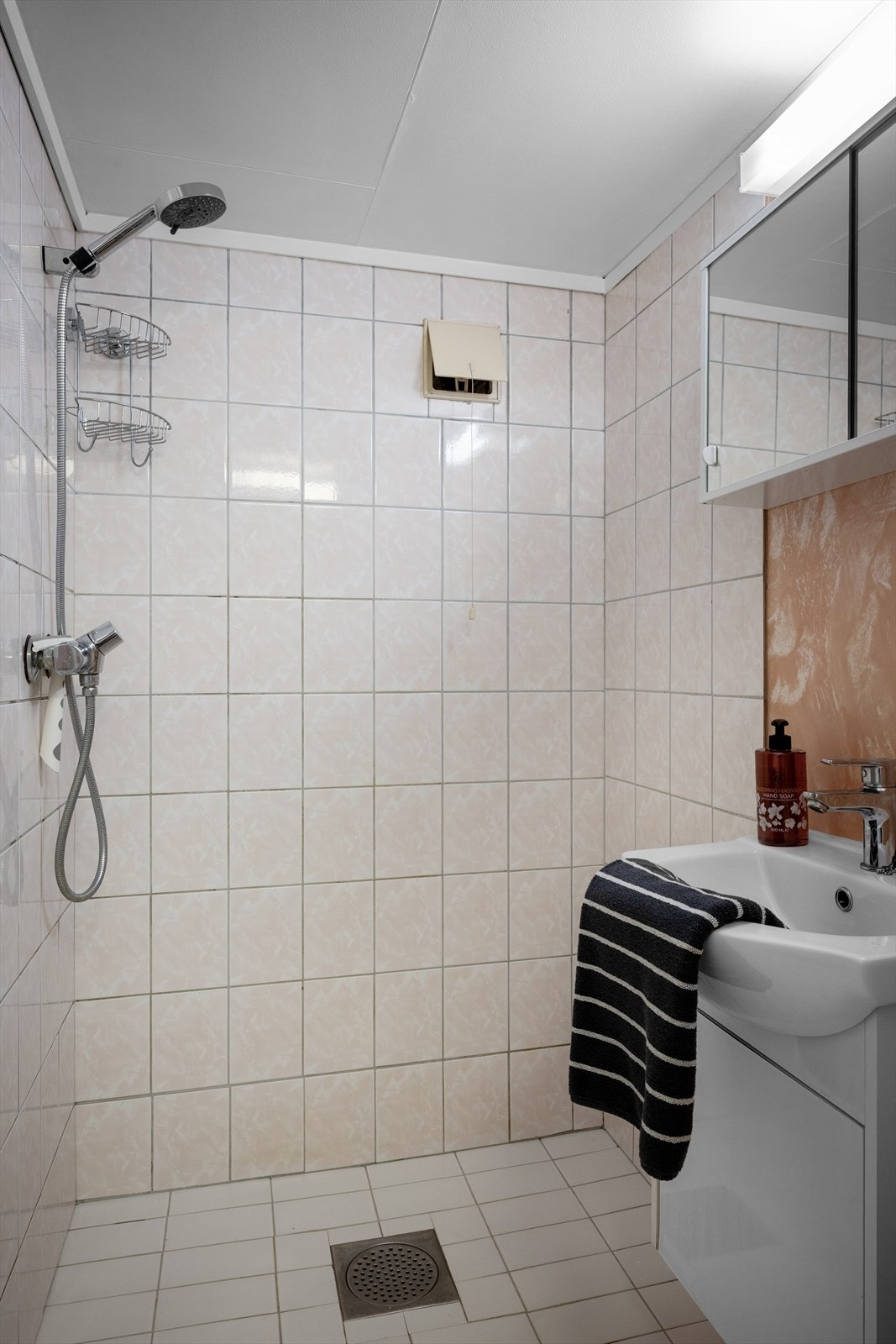 Et enkelt bad i underetasjen med fliser og varme i gulv. Innredet med vask, dusj, wc og håndkletørker. Galleribilde