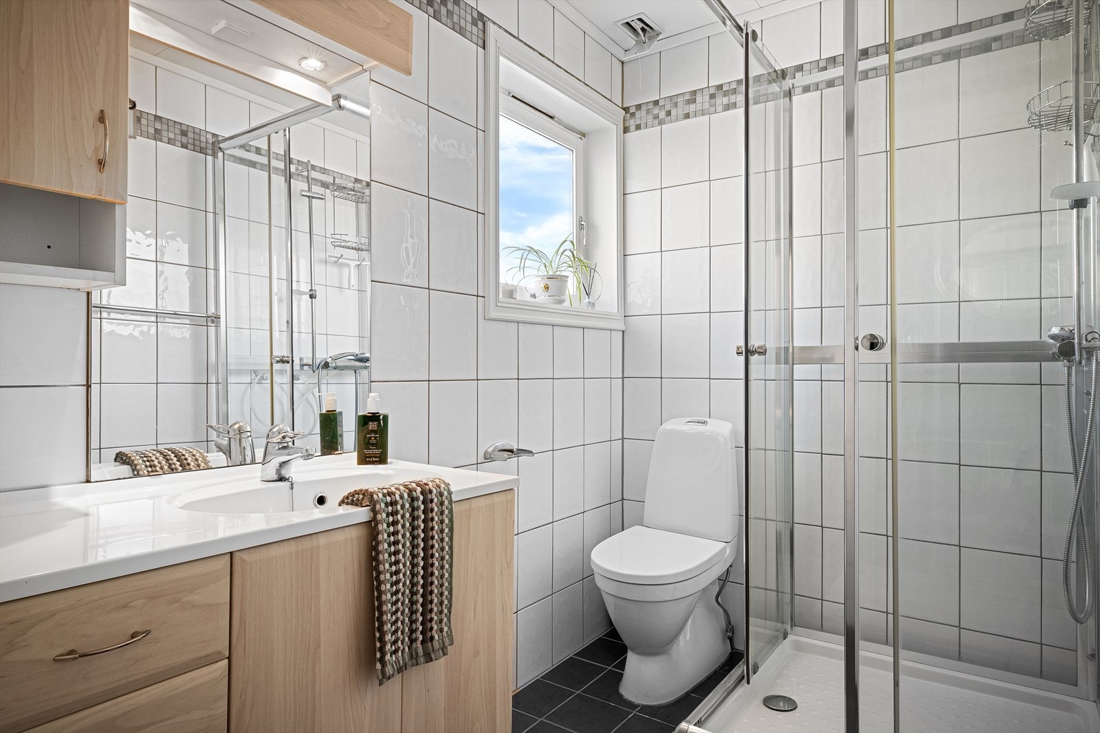 Leilighet - Dykjelsletta 36A. Helfliset bad med varme i gulv. Innredet med vask i seksjon, dusjkabinett og WC. Galleribilde