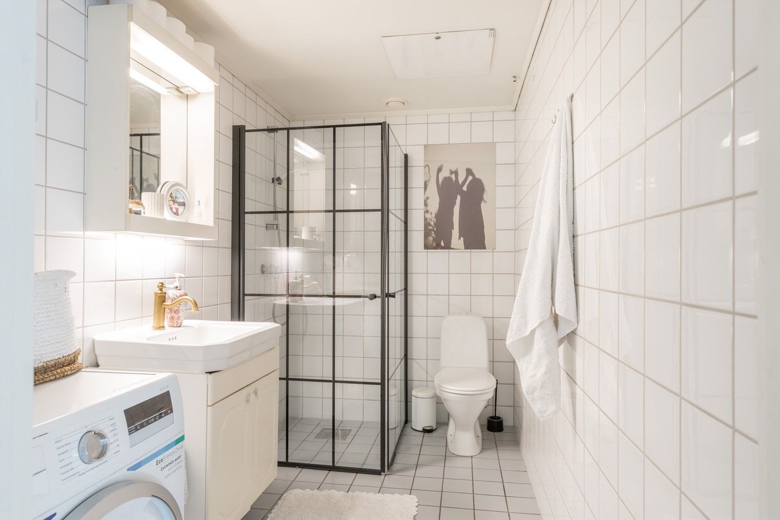 Bad fra 1998 med fliser på vegger og gulv. Innredning med benkeskap med profilerte fronter og speil over servant. Dusj med innfellbare glassdører, gulvstående toalett og opplegg for vaskemaskin. Galleribilde
