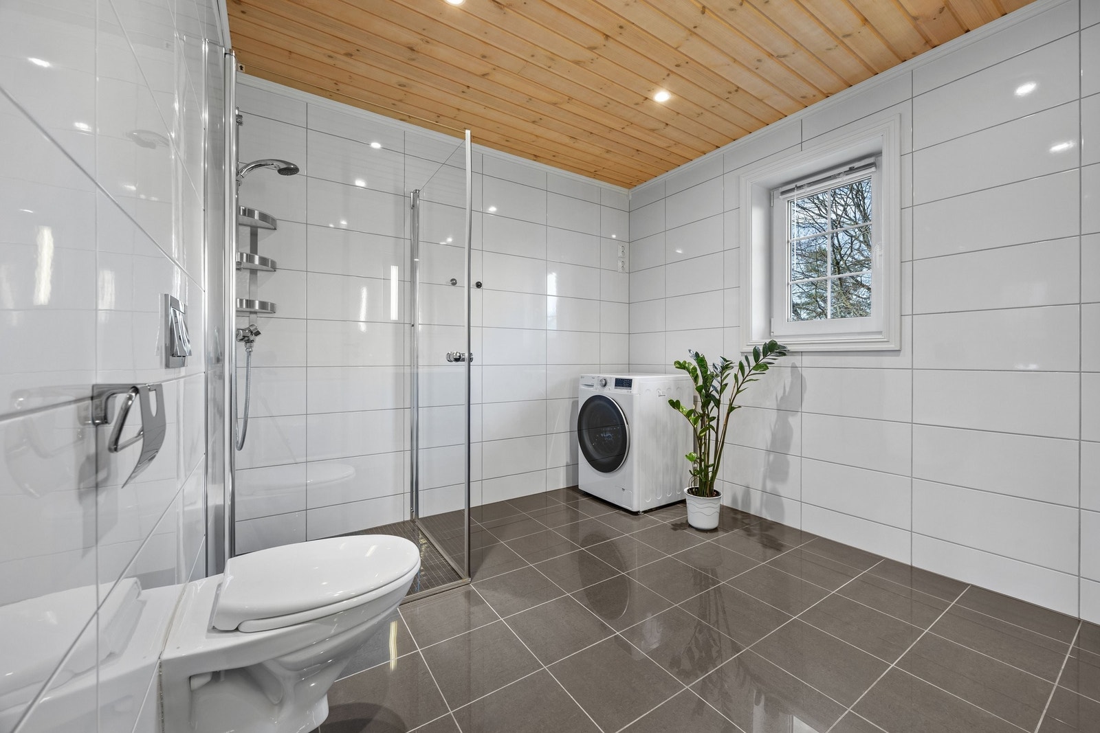 Stort, moderne bad med romslig dusjsone og opplegg for vaskemaskin. Galleribilde