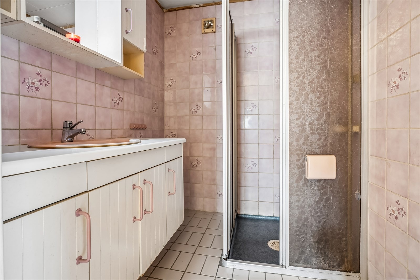 Badet i første etasje er et eldre våtrom med fliser på vegger, belegg på gulv, dusjvegger og mekanisk avtrekk. Galleribilde