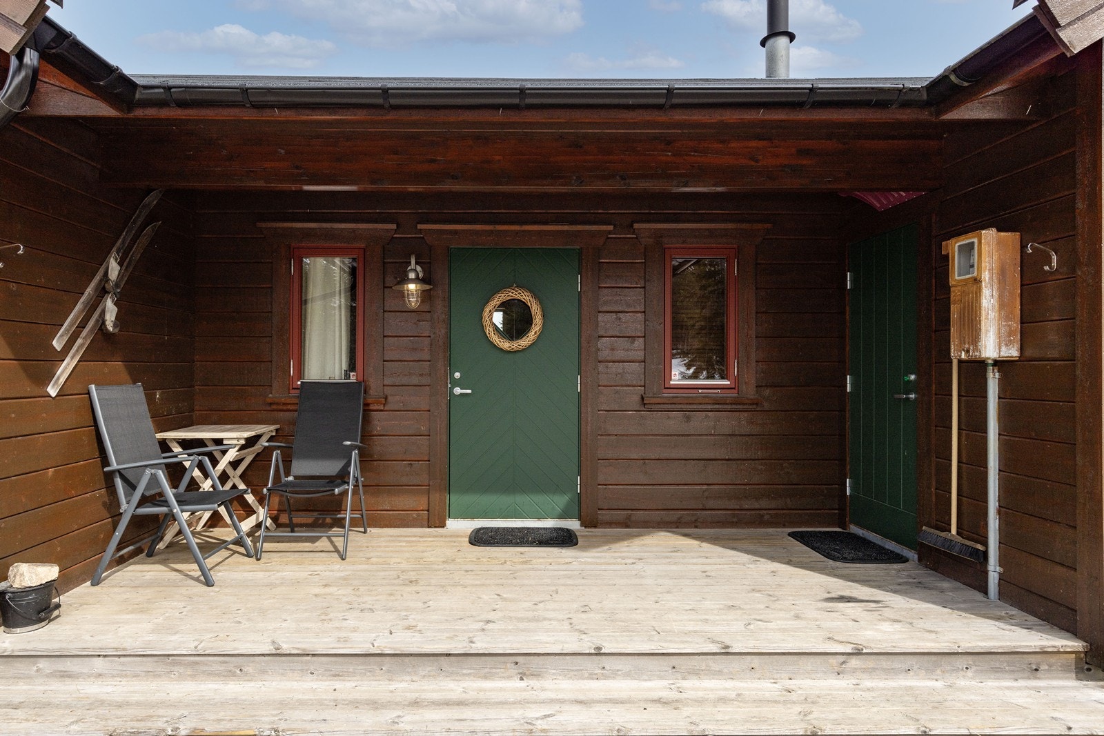 Overbygget inngangsparti med plass til en liten sittegruppe. Galleribilde