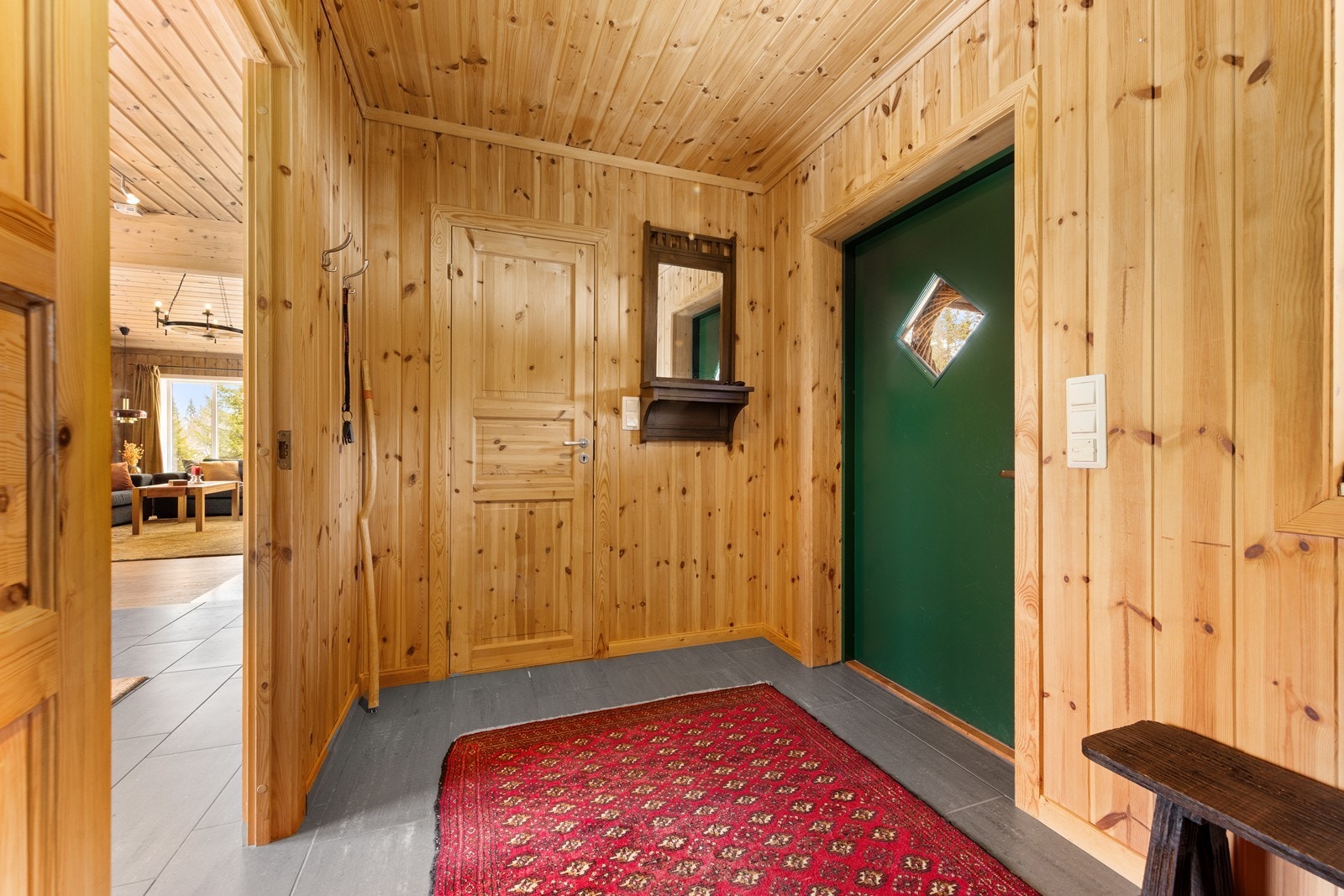Vindfanget tar deg inn i hyttas hall. Gjennomgående er det panel på vegger og i tak, og heltre fyllingsdører mellom rommene. Galleribilde