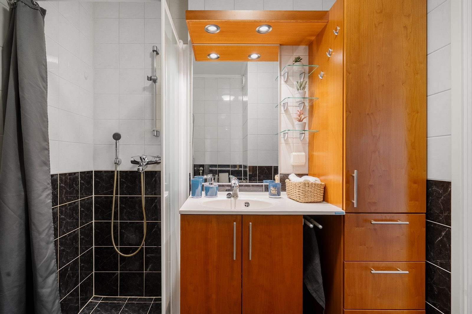 Badet er innredet med dusjvegger, toalett, servant med innredning og speil med belysning - Opplegg for vaskemaskin Galleribilde